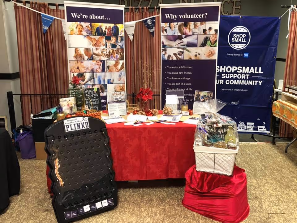 Indoor booth setup with banners, a red tablecloth, and promotional materials.