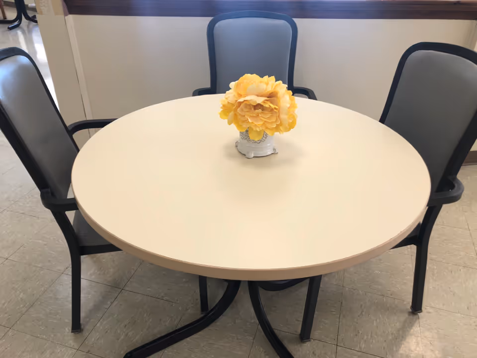 Round dining table with four chairs and a yellow flower centerpiece