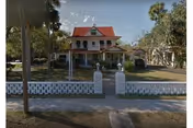 Magnolia Manor Assisted Living's two-story building, white fence, front yard, and mature trees.