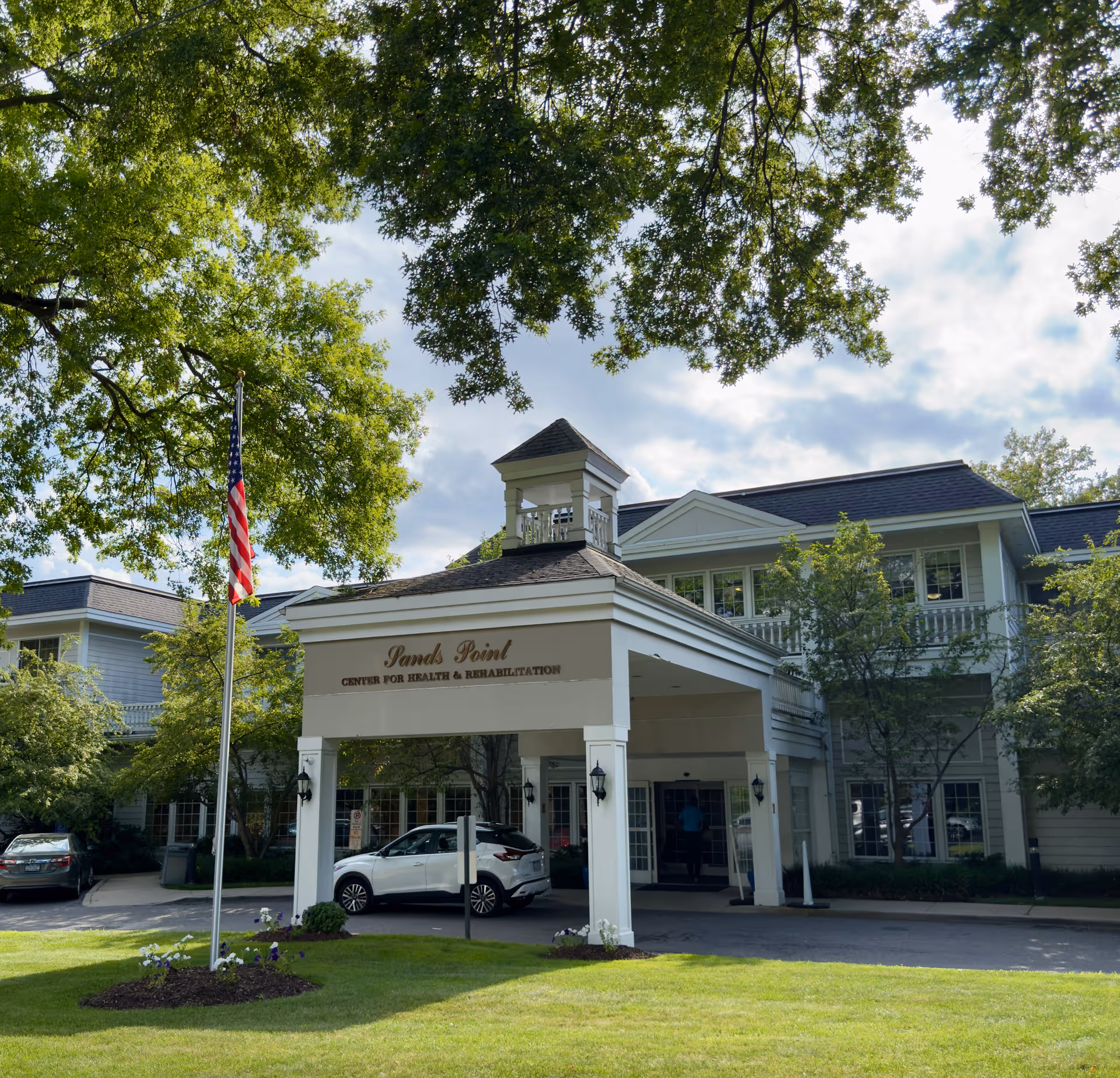 Sands Point Center for Health and Rehabilitation building entrance with flag and trees visible.