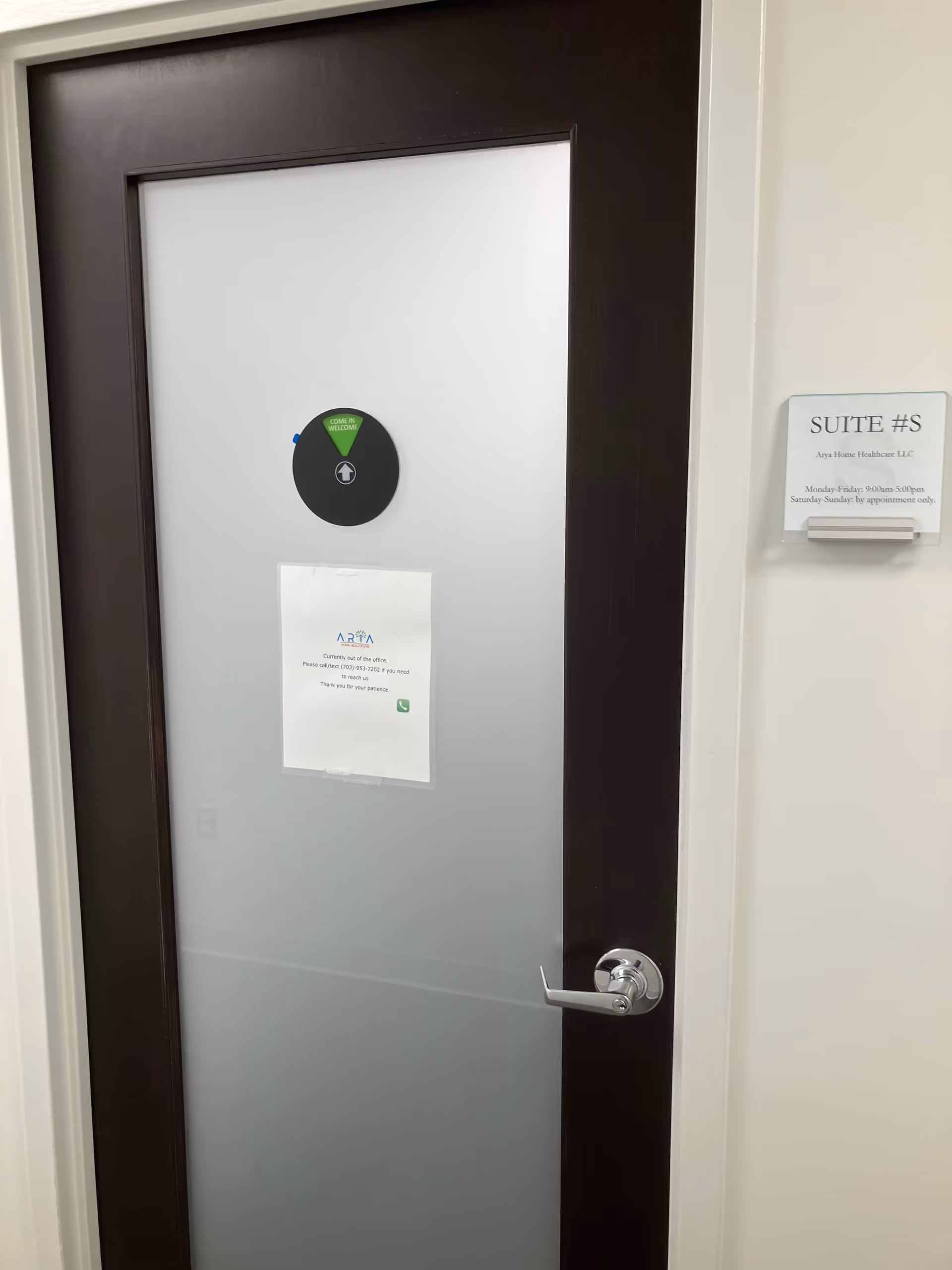 Interior door with frosted glass, metal handle, and suite sign in hallway.
