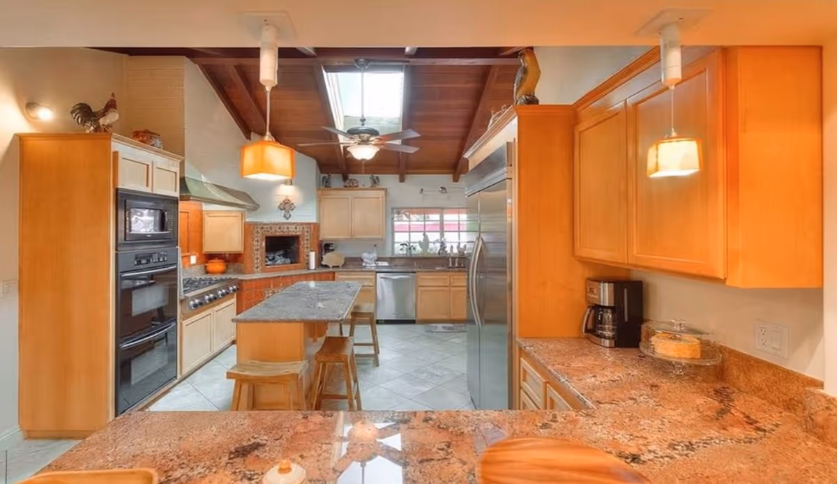 Open-concept kitchen with granite countertops, island, and wooden cabinets.