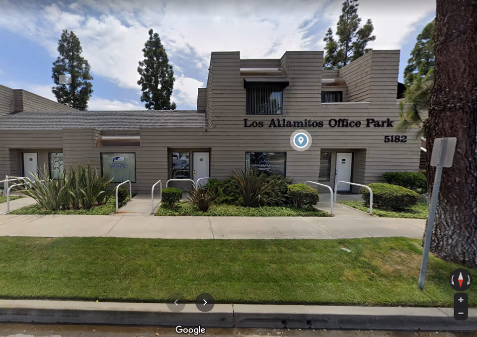 Front view of a beige office building with landscaping in Los Alamitos Office Park.