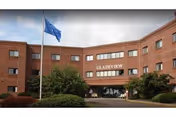 Brick exterior of Gladeview Health Care Center with entrance and flag.