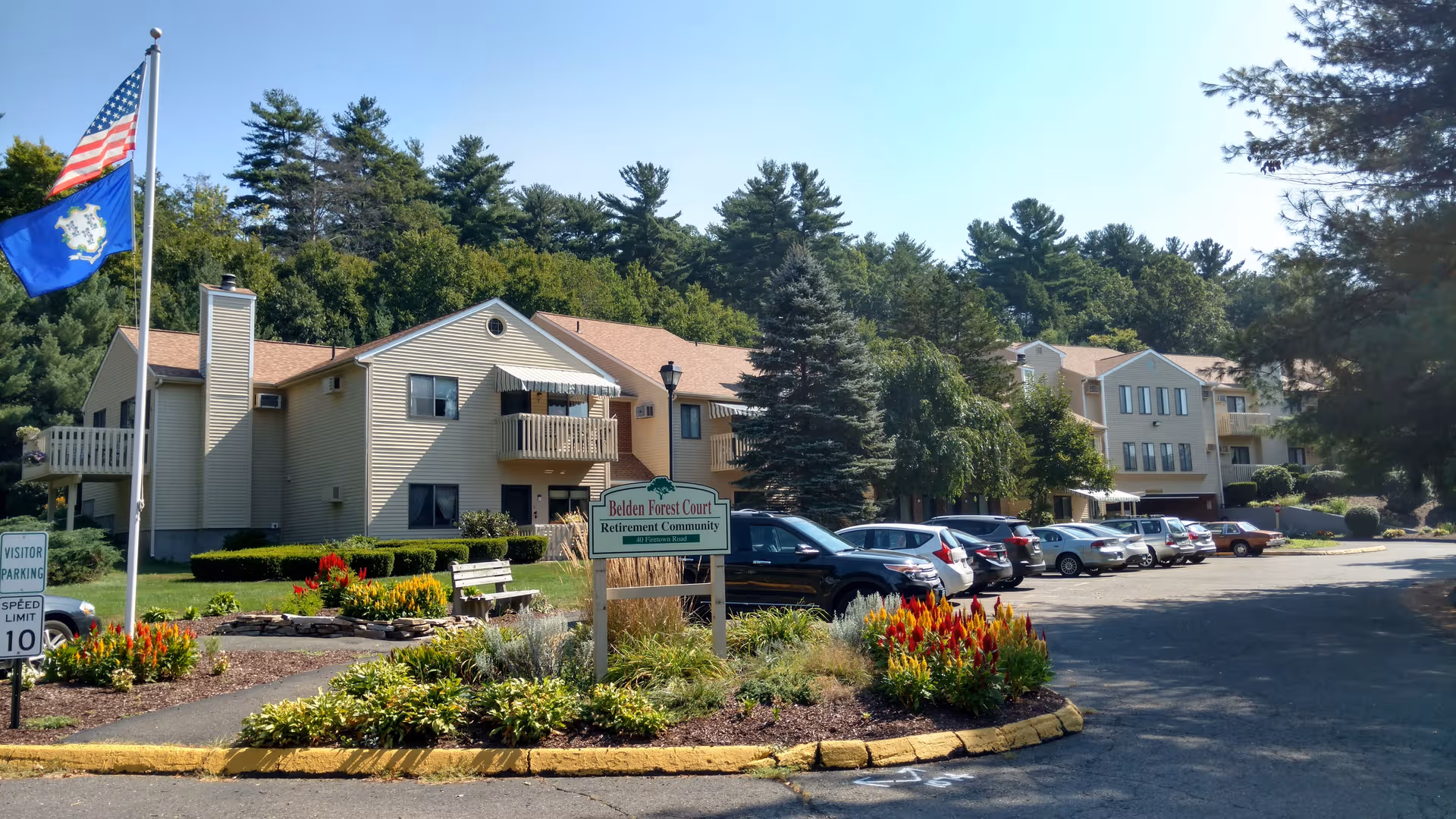 Exterior view of Belden Forest Court retirement community with parked cars.