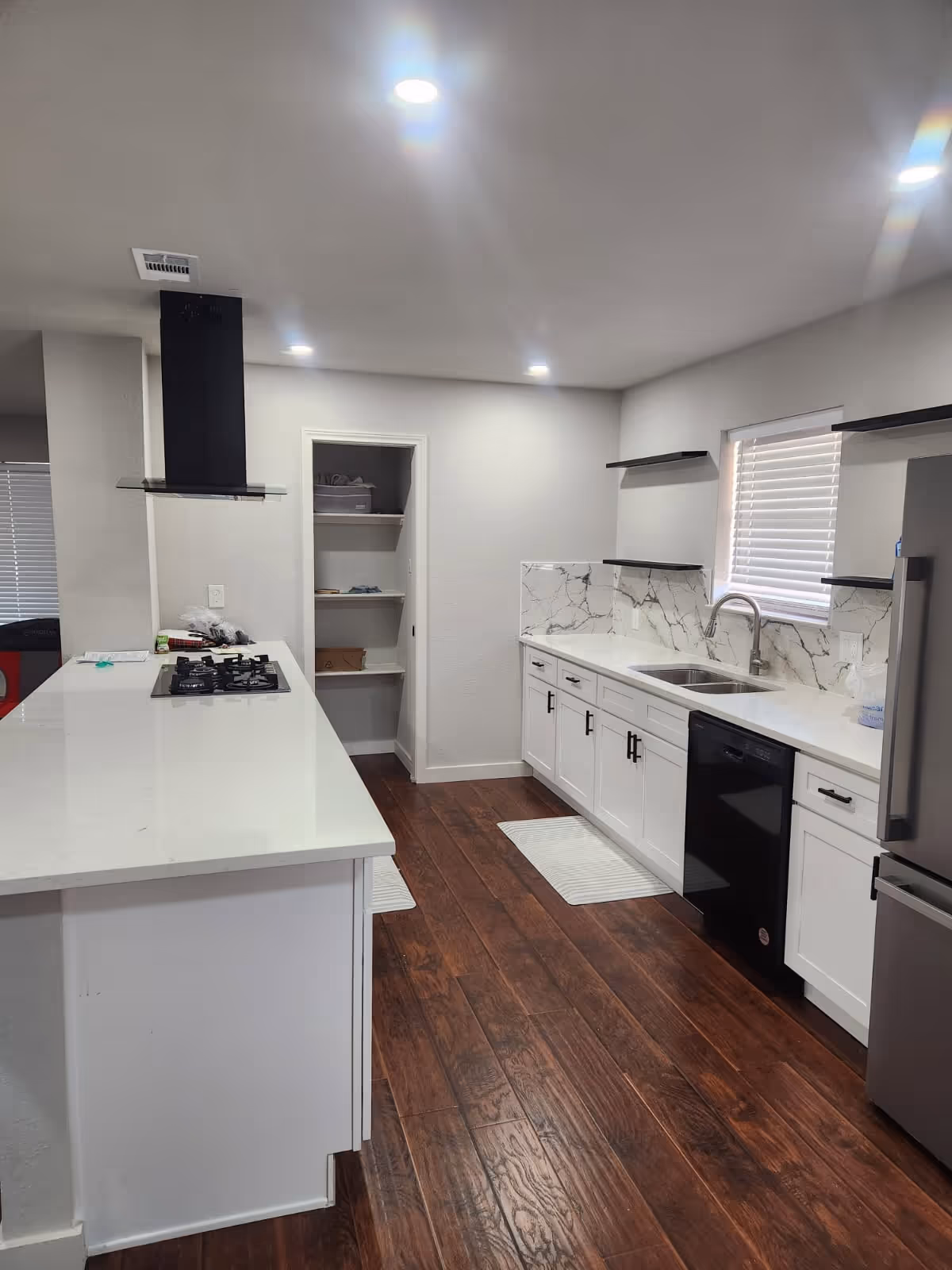 Bright white kitchen with island, stainless appliances, and marble backsplash.