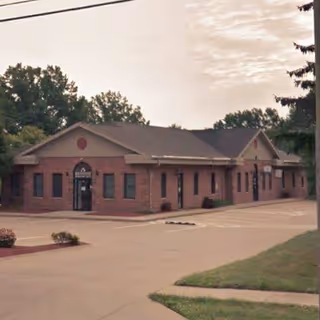 Exterior brick building with a parking lot and surrounding trees.