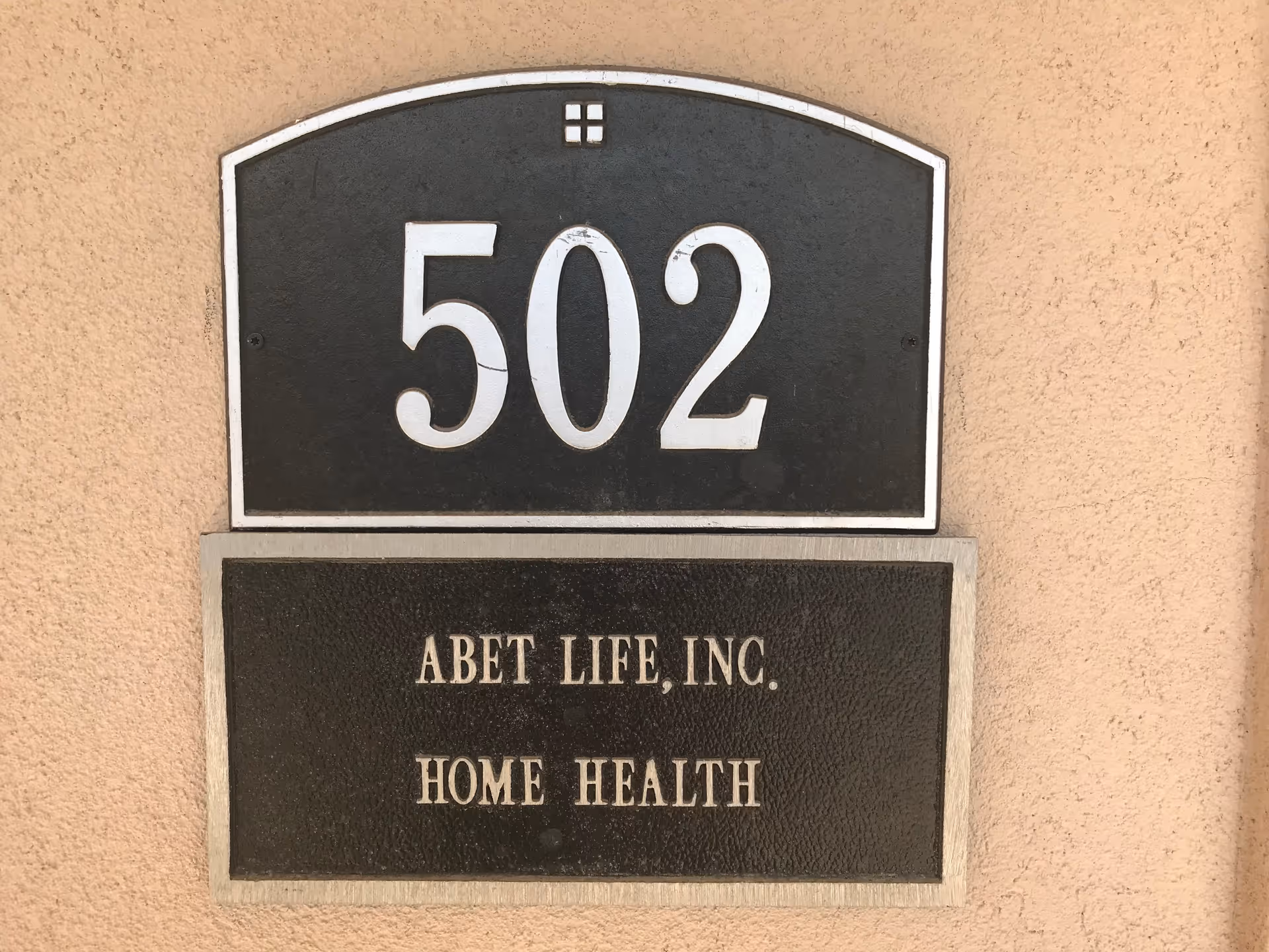 Tan exterior wall with a 502 house number plaque and ABET LIFE, INC. Home Health sign.