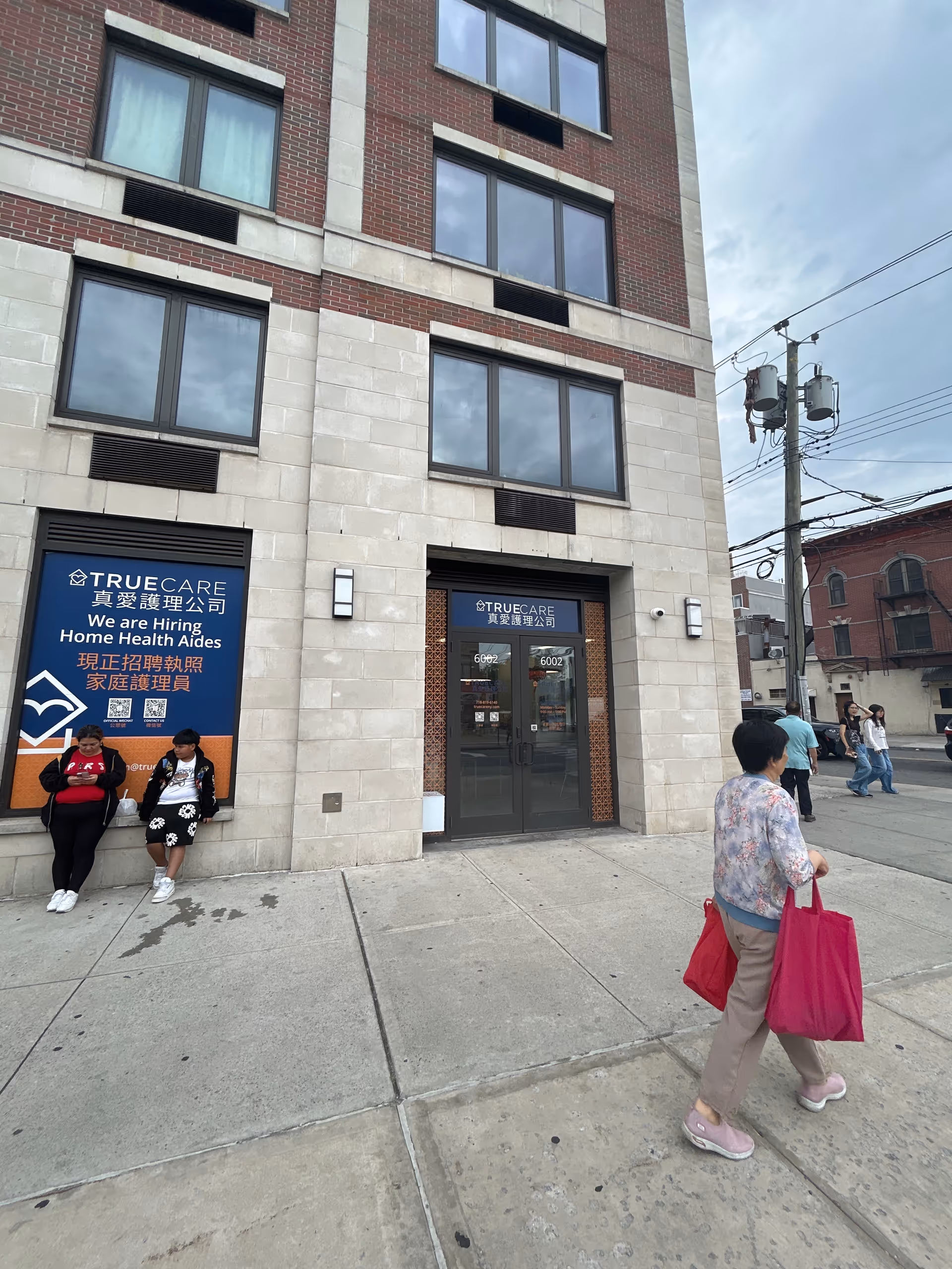 Exterior view of a building entrance with TrueCare signage and people outside.