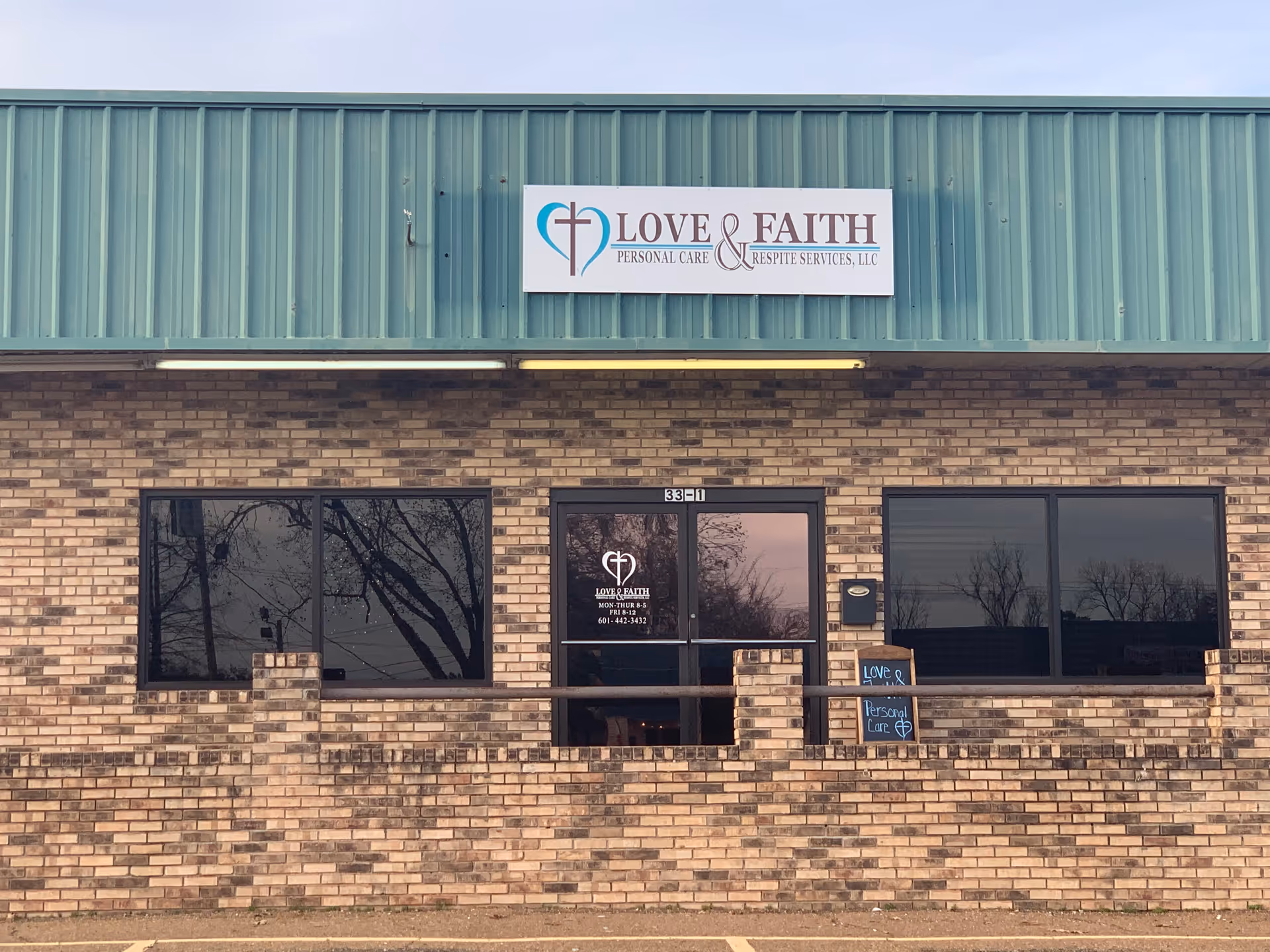 Brick storefront with Love and Faith sign and glass doors.