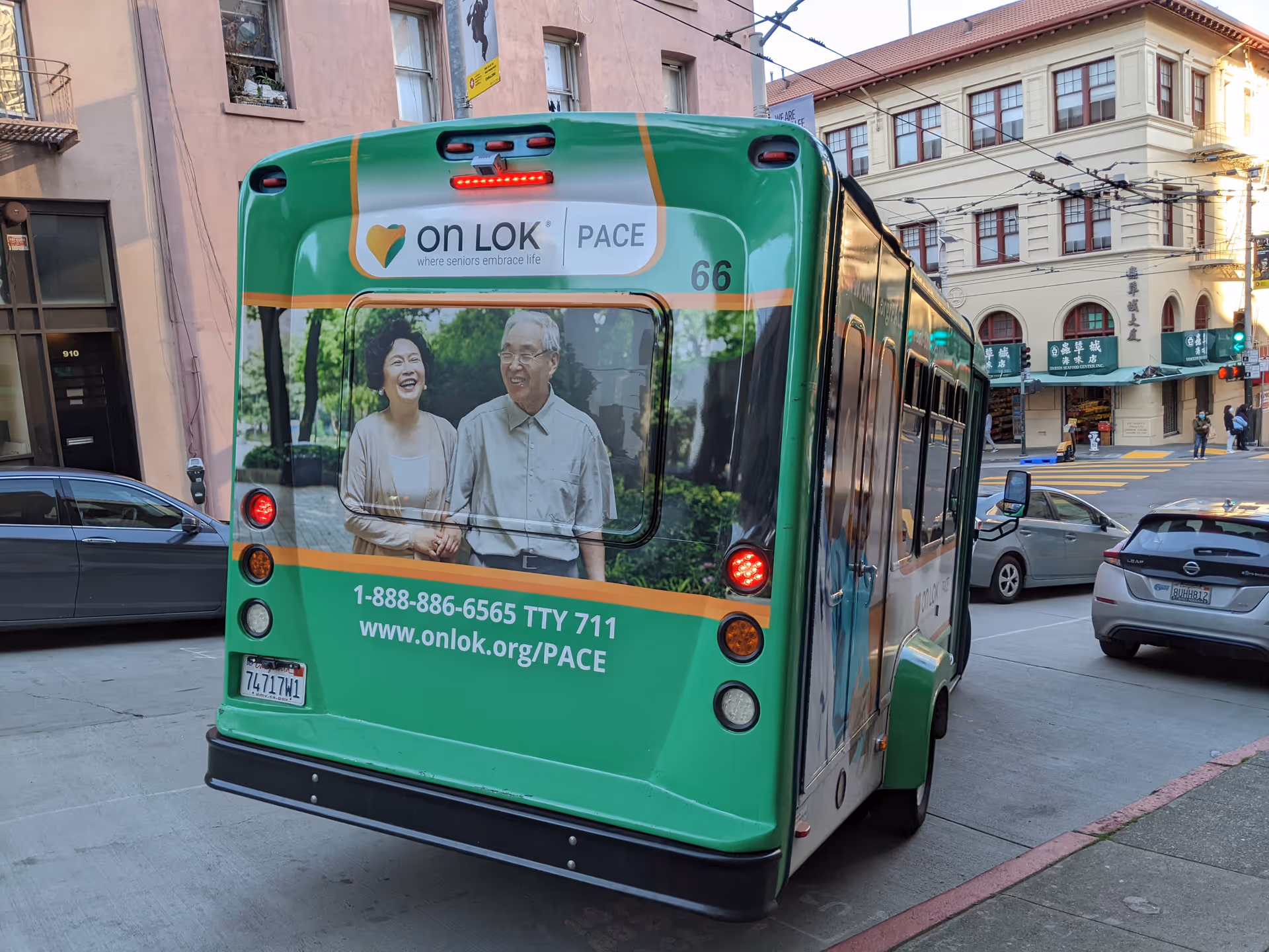 Rear view of a green On Lok PACE bus on a city street with surrounding buildings.