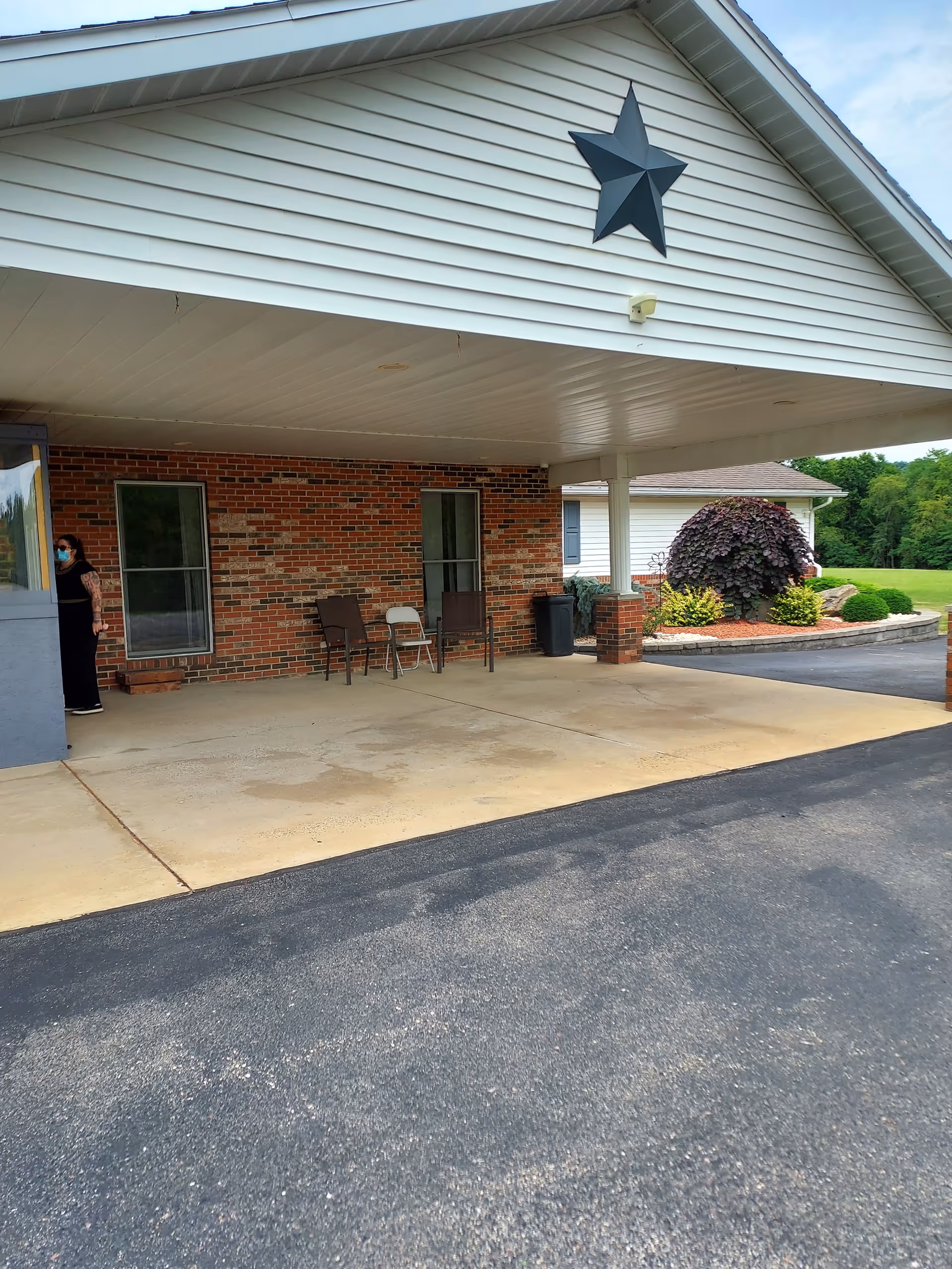 Brick facility exterior with a covered entry and seating on the front porch.