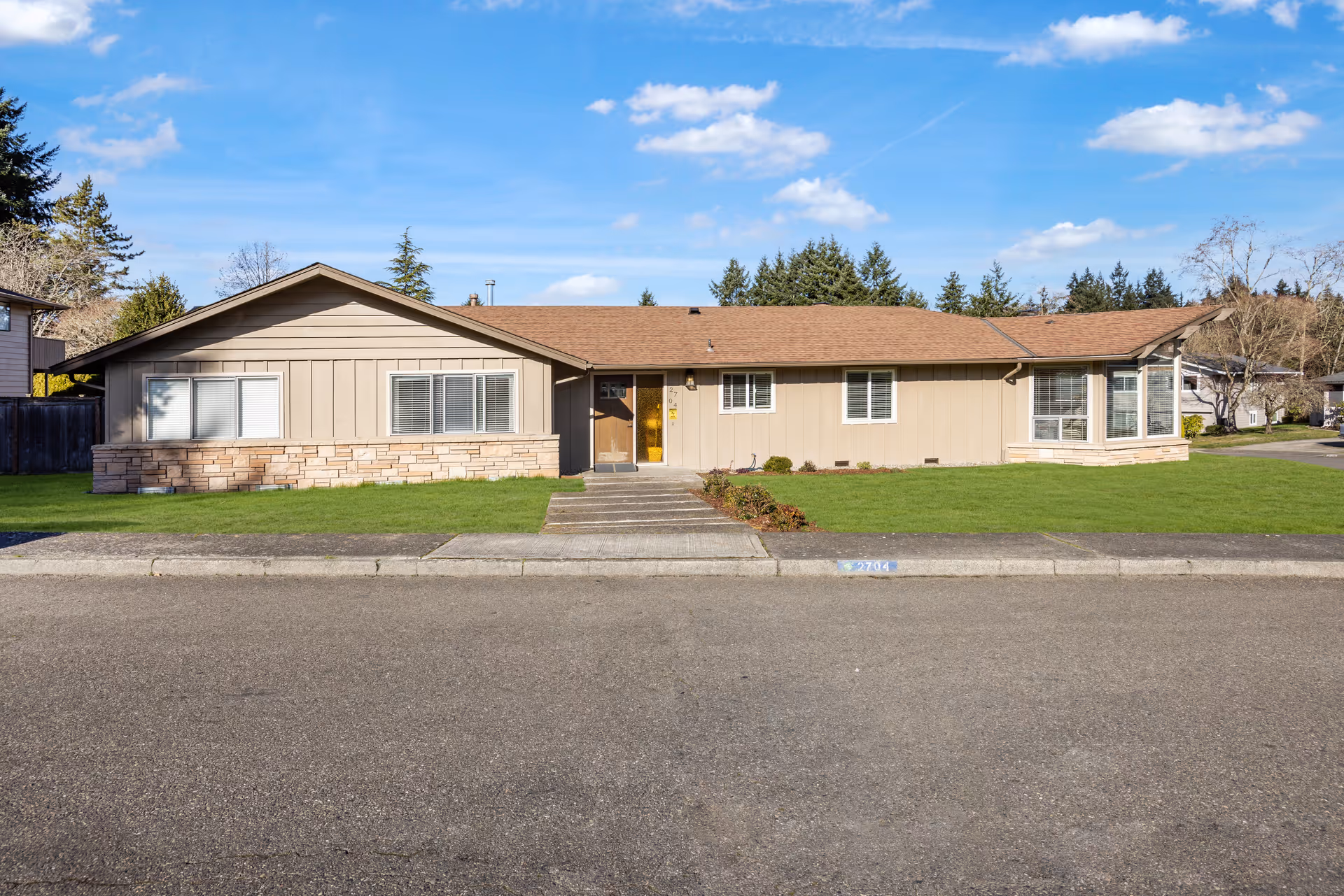 Single-story beige senior living facility with a green lawn and front entrance.