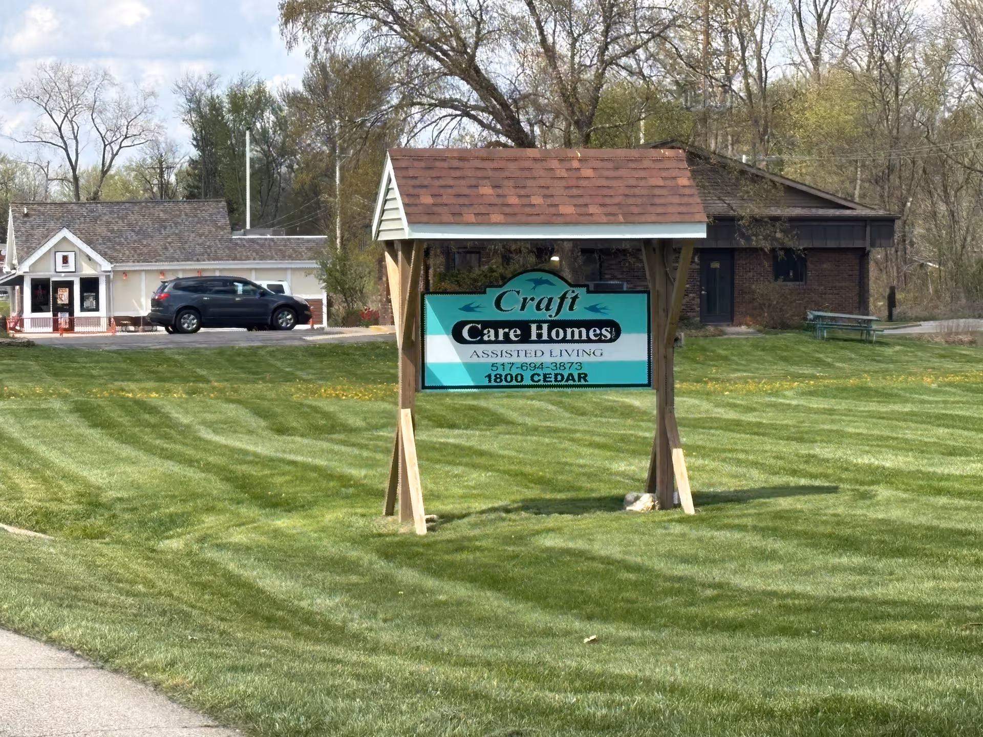 Outdoors sign for Craft Care Homes on a green lawn with a building behind.