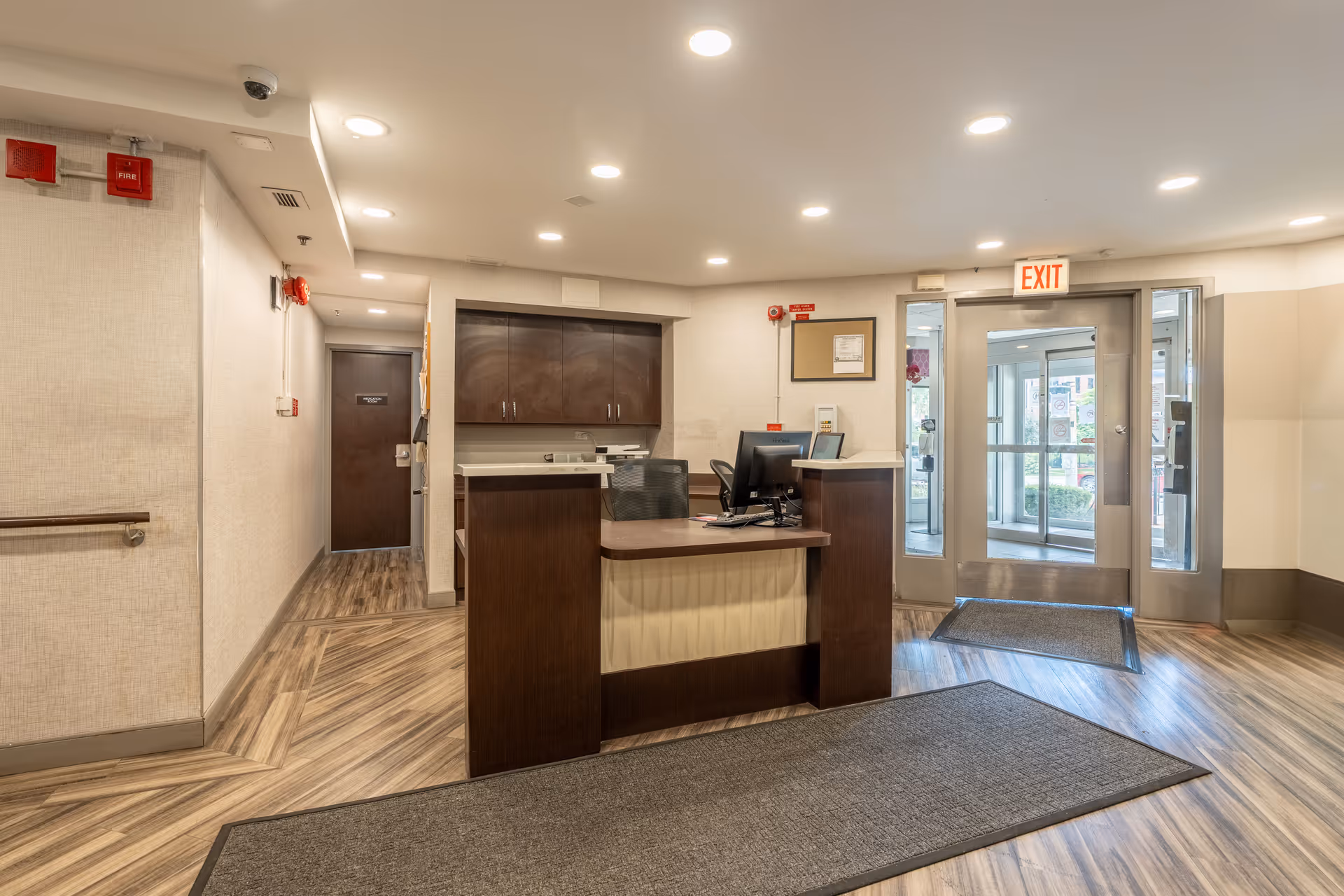 Reception desk in a senior living facility lobby with glass entry doors