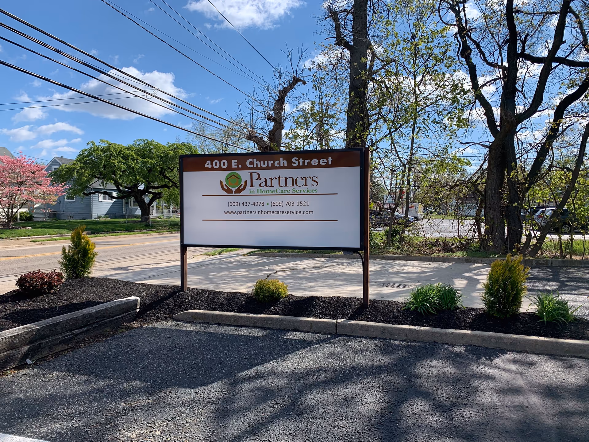Exterior street view featuring a sign for Partners in HomeCare Services and surrounding landscaping.