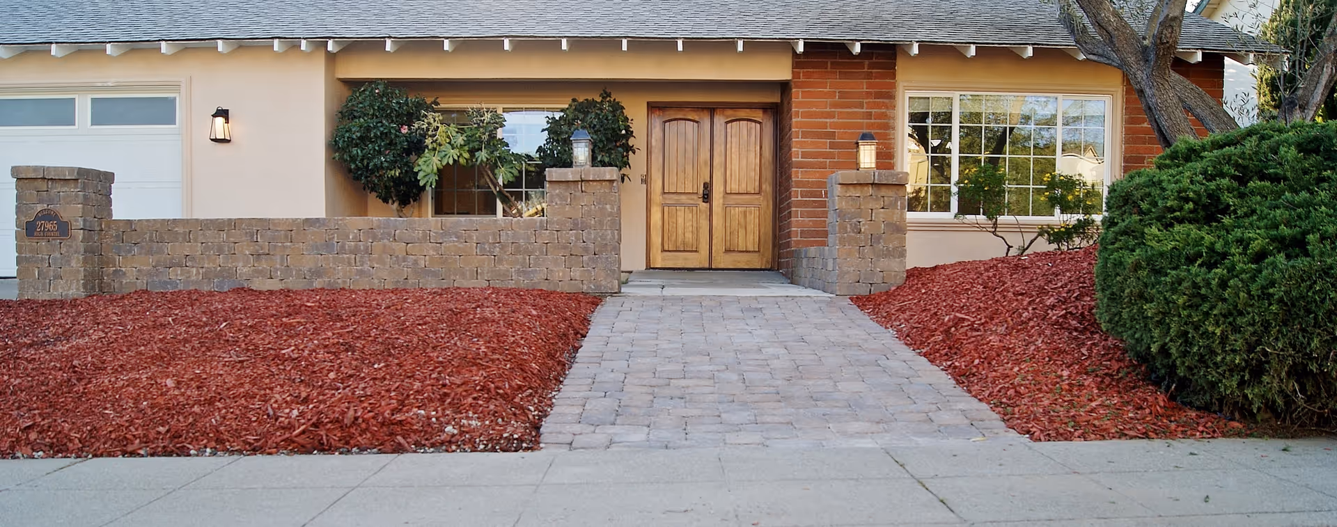 Exterior view of senior care center entrance with brick facade, wooden doors, and landscaped path.