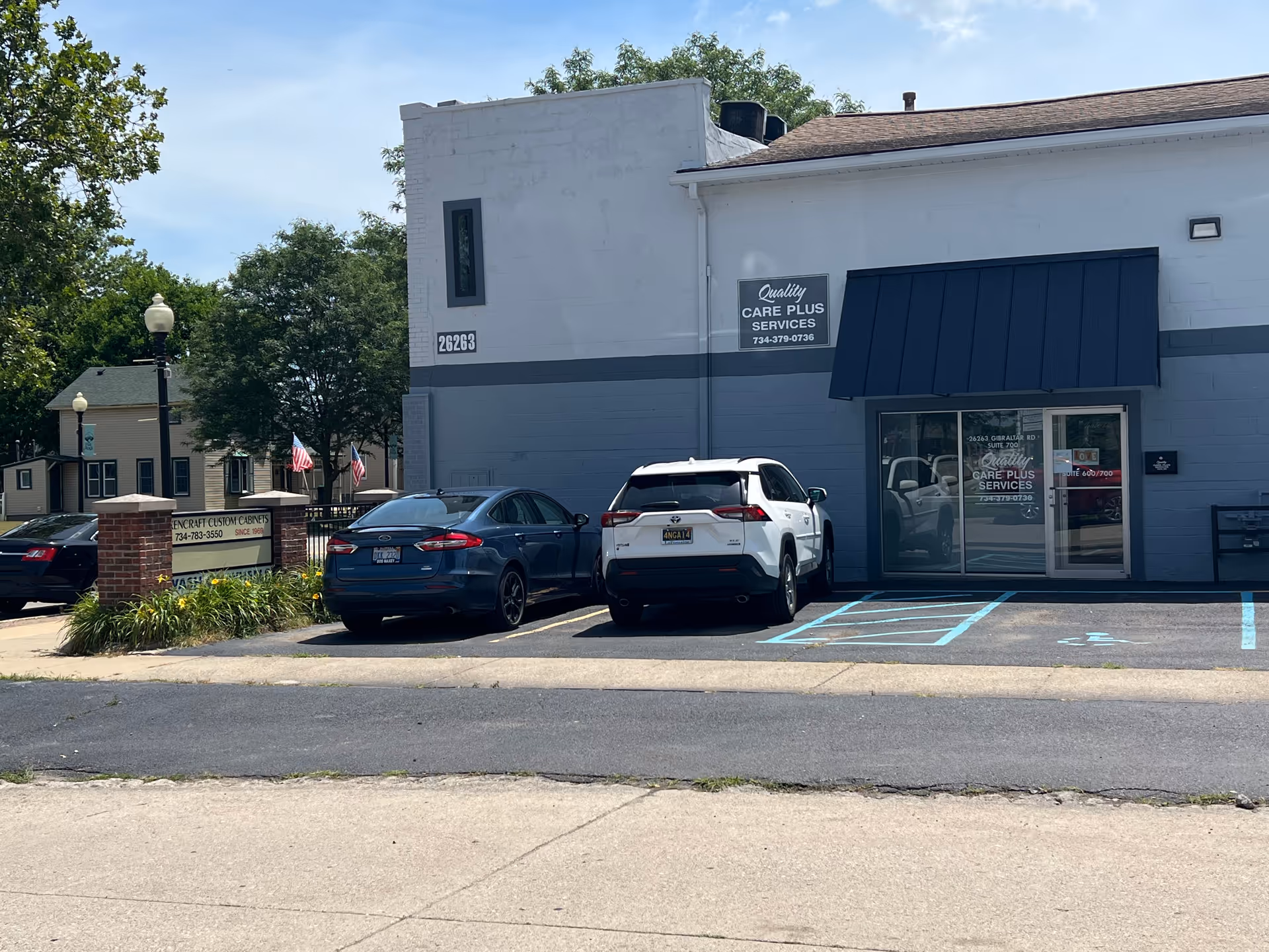 Front view of Quality Care Plus Services LLC building with blue awning and parked cars.