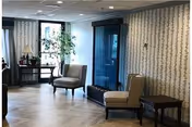 Bright lounge area with patterned wallpaper, armchairs, and glass doors.