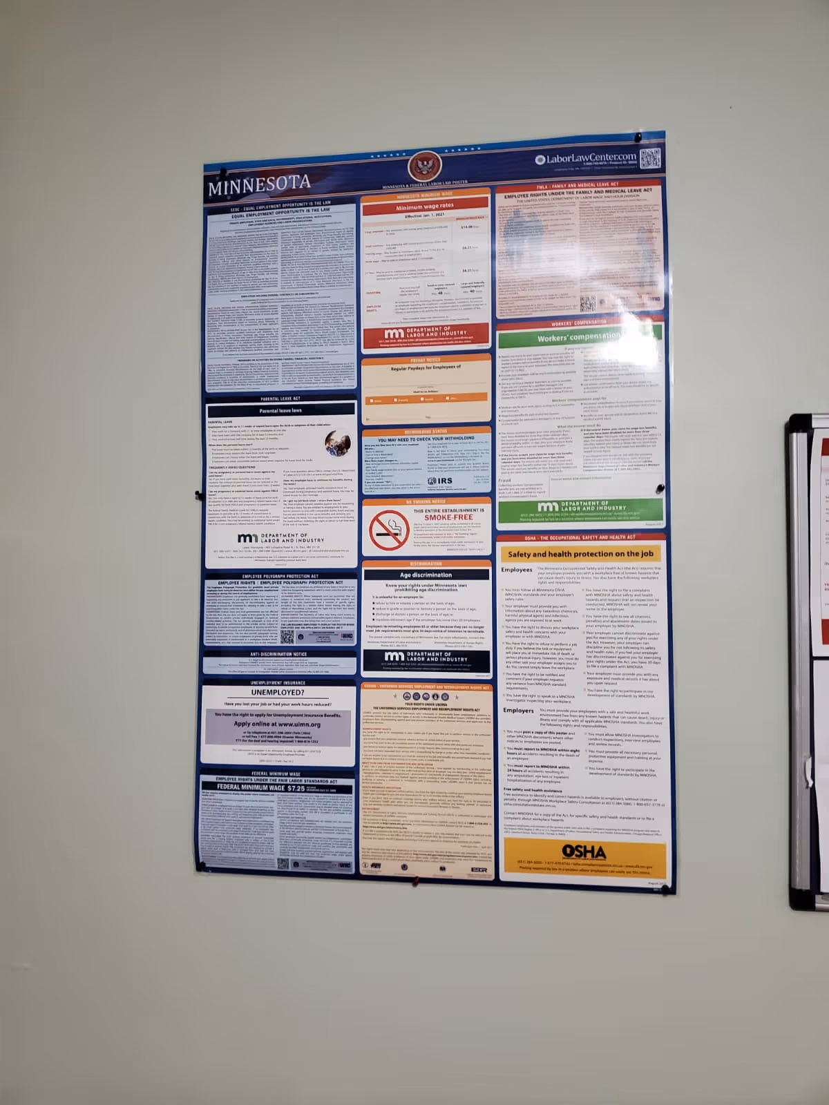 Large multi-panel informational poster mounted on a pale hallway wall inside a facility.