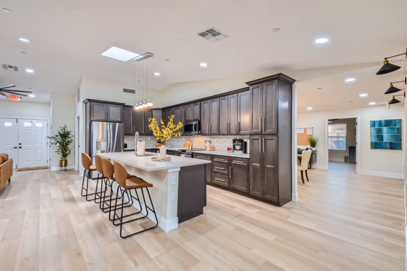 Bright commercial-style kitchen in Elite Serenity with dark cabinets, island seating, stainless appliances.