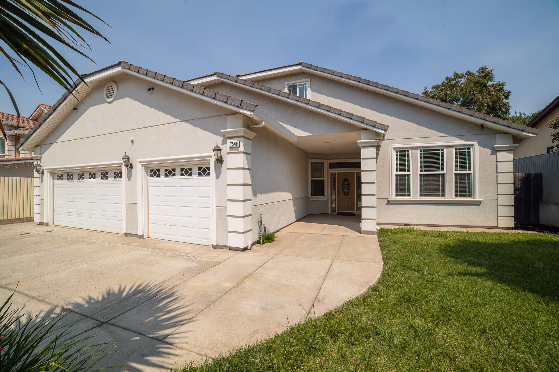 A single-story residential building with a concrete driveway, garages, and a covered front entry.