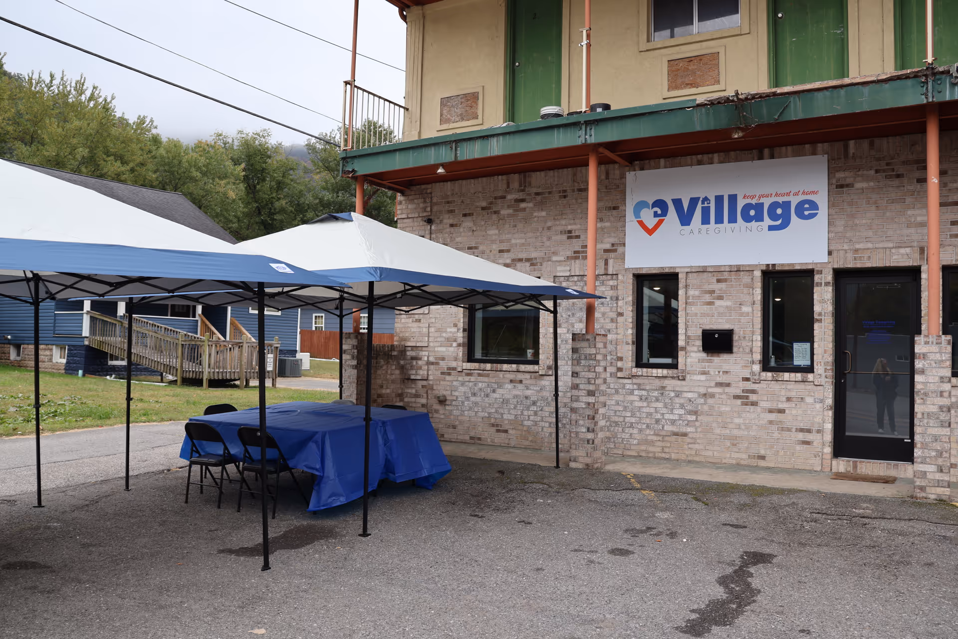 Outside Village Caregiving facility with blue tents, tables, and chairs.