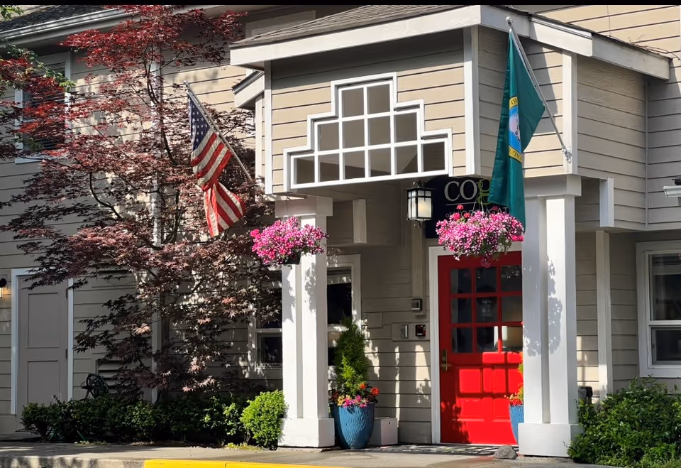 Cogir of Northgate entrance with bright red door, flags, and hanging flower baskets.