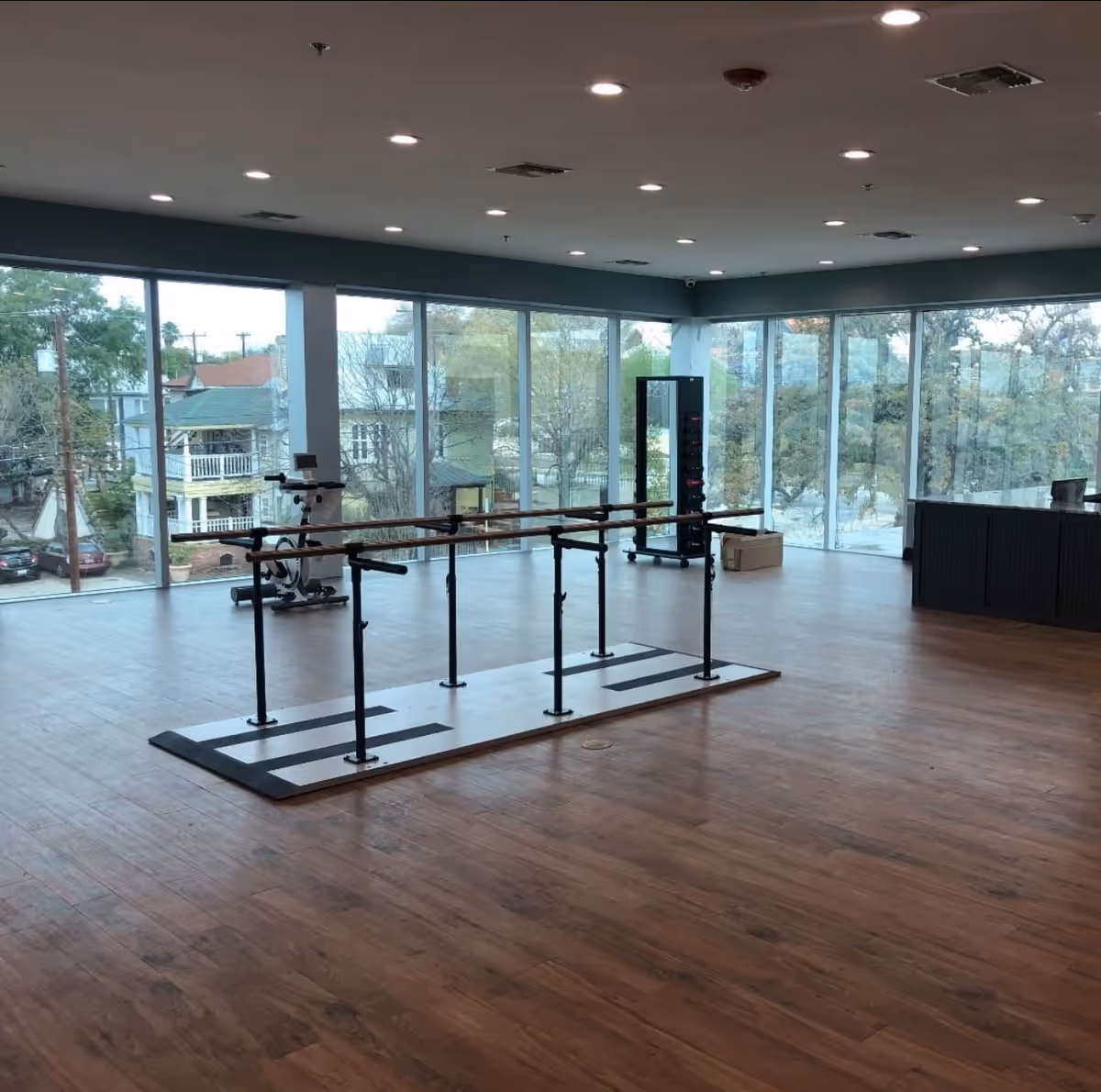Interior fitness room with parallel bars and large glass windows.