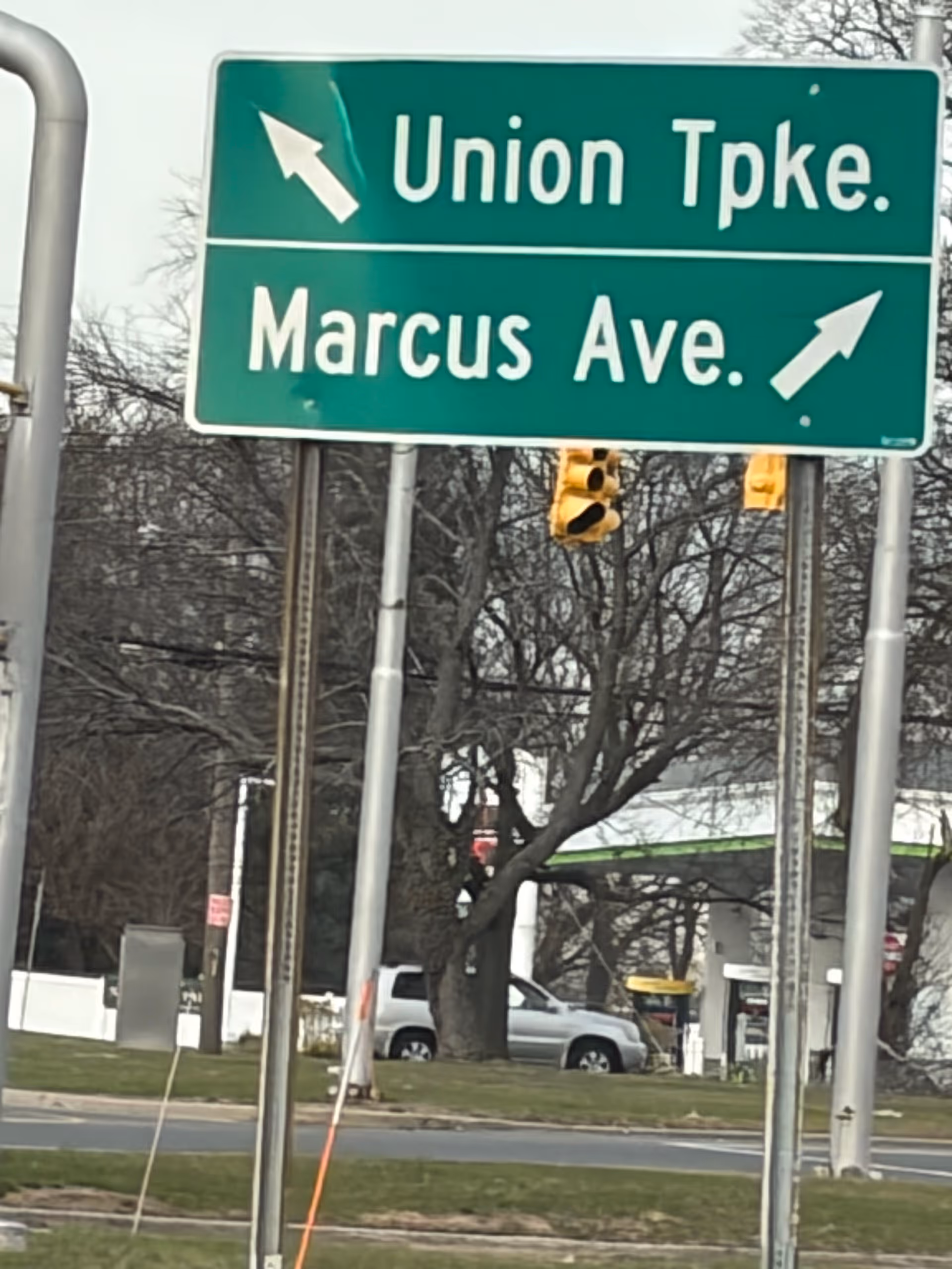 Green street sign overhead showing Union Tpke and Marcus Ave with traffic lights.