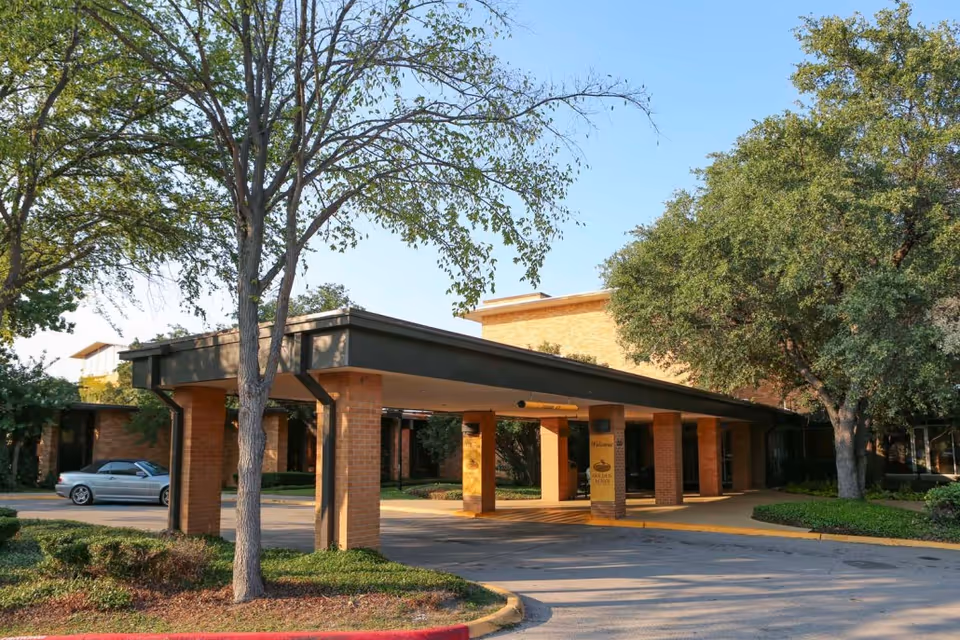 Exterior view of a brick building with a covered entrance and trees.