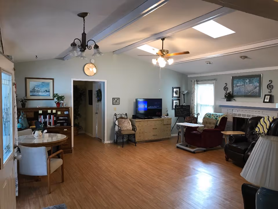 Cozy senior living room with ample seating, TV, fireplace mantel, and soft blue walls.