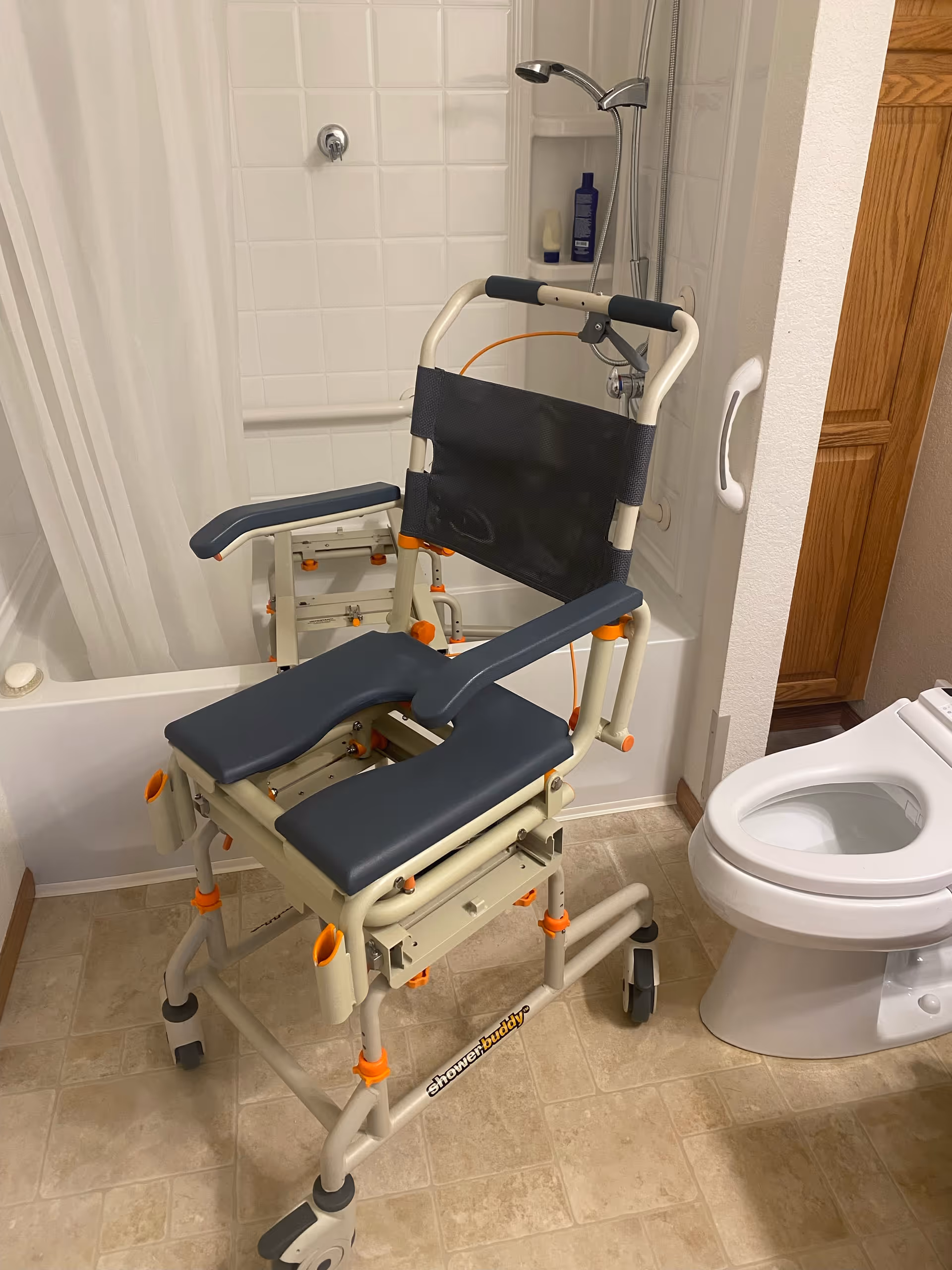 Wheeled assistive shower chair with backrest in a tiled bathroom beside a toilet