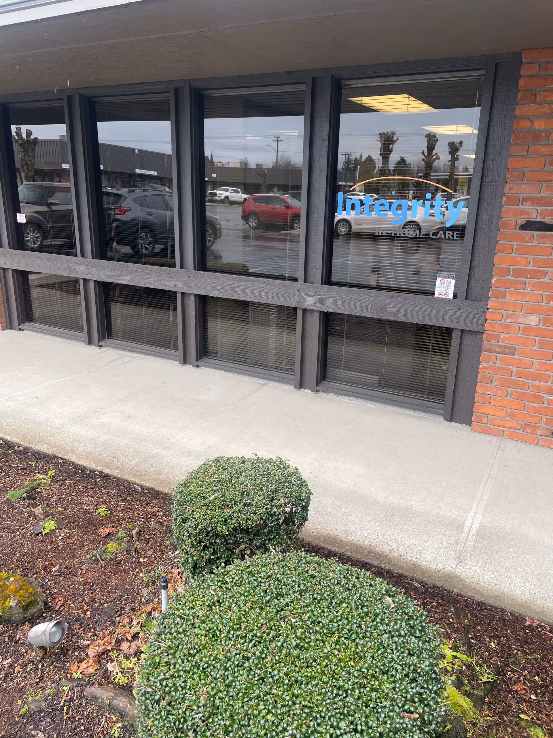 Exterior view of Integrity In Home Care Salem with large windows and shrubs.