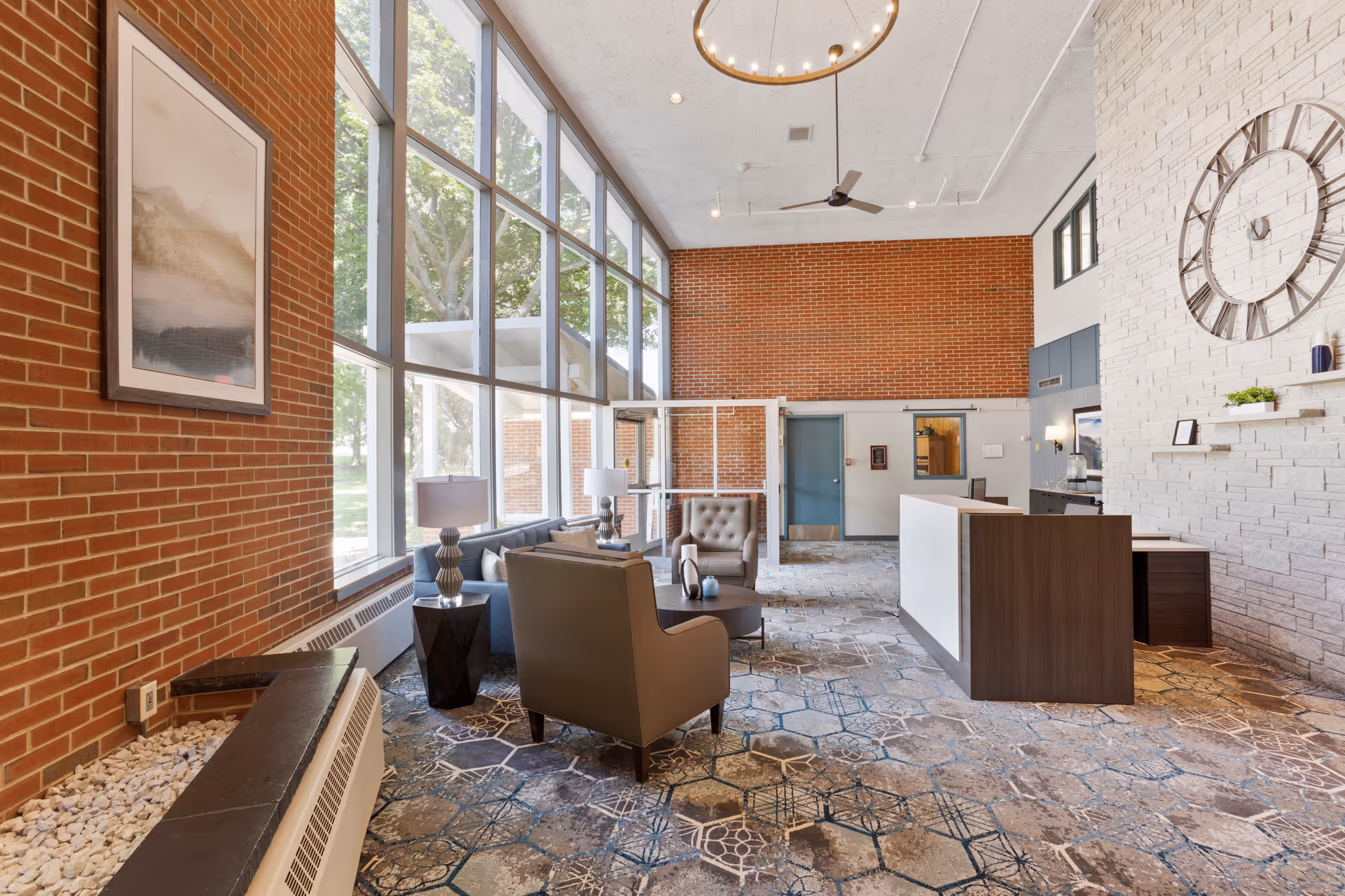 Bright lobby with brick walls, large windows, seating, and a reception desk.