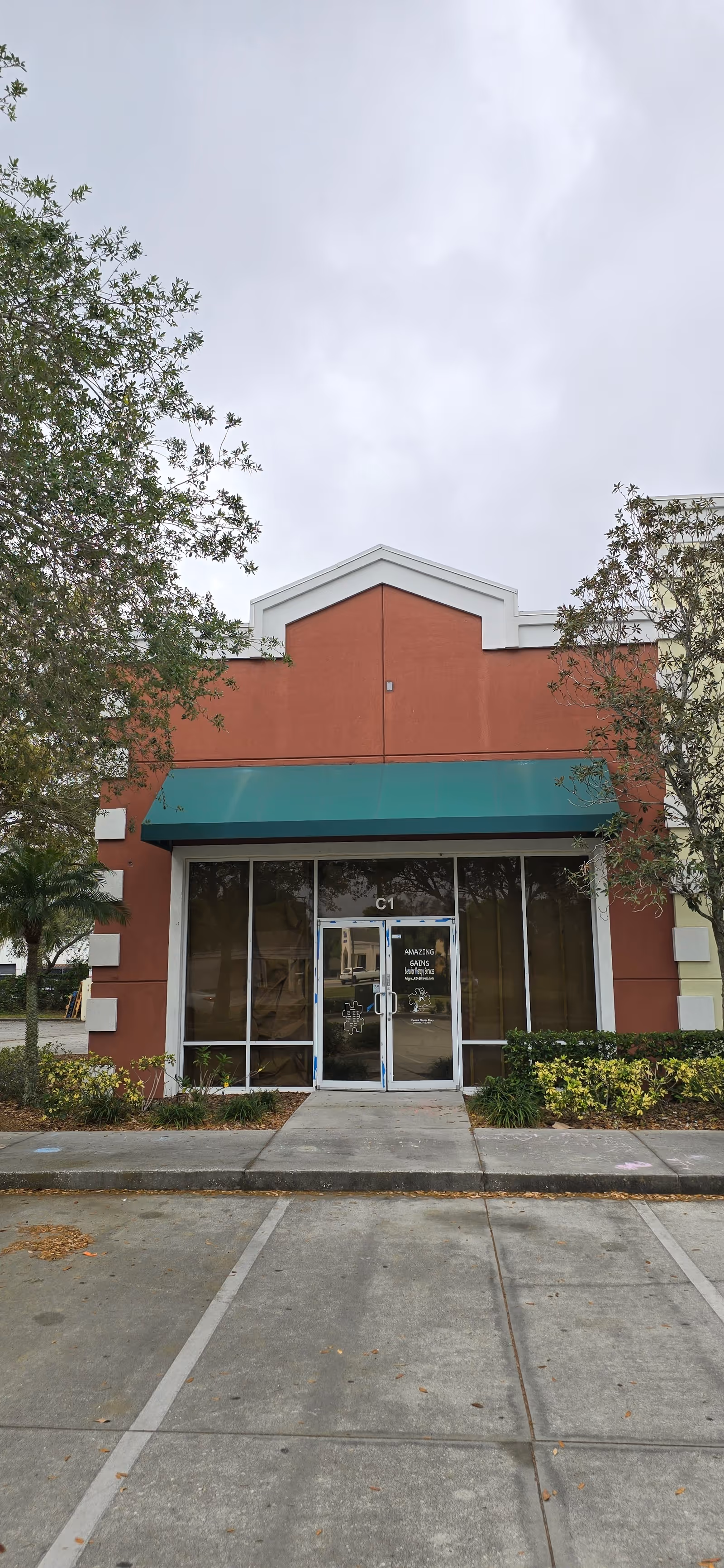 Front view of a brick building with a green awning and glass entrance.