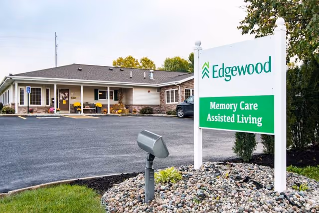 Exterior view of Edgewood Omaha Senior Living with a green and white sign and parking lot.