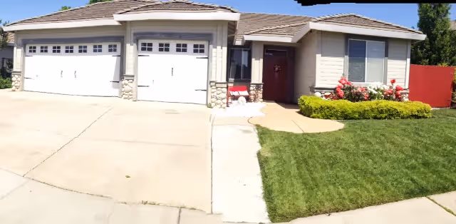 Front exterior of a suburban residential care home with a two-car garage and manicured lawn.