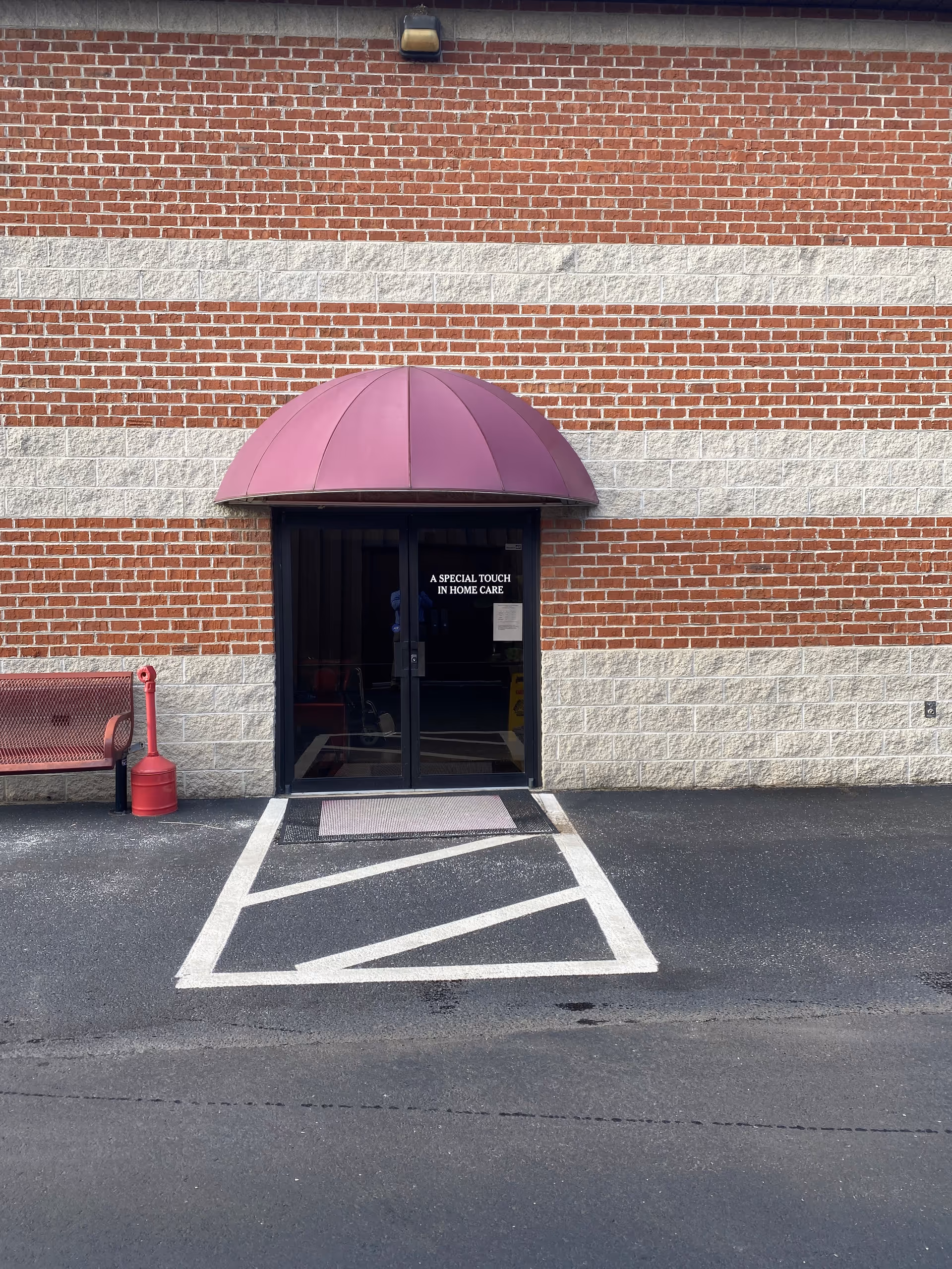 Brick exterior with a purple curved awning over glass entry doors.