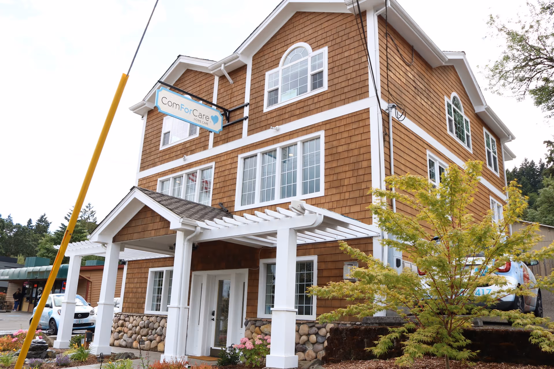 Three-story brown shingle building with white trim and a ComForCare sign at the entrance.