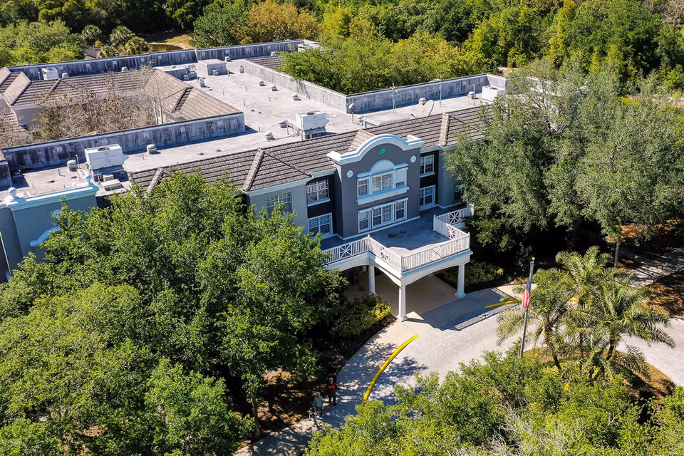 Aerial view of Tampa Gardens Senior Living exterior with front entrance and surrounding trees