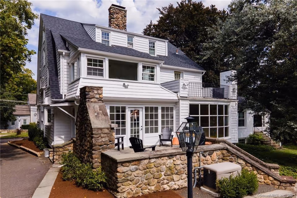 White multi-story senior living building with a stone terrace and outdoor seating.