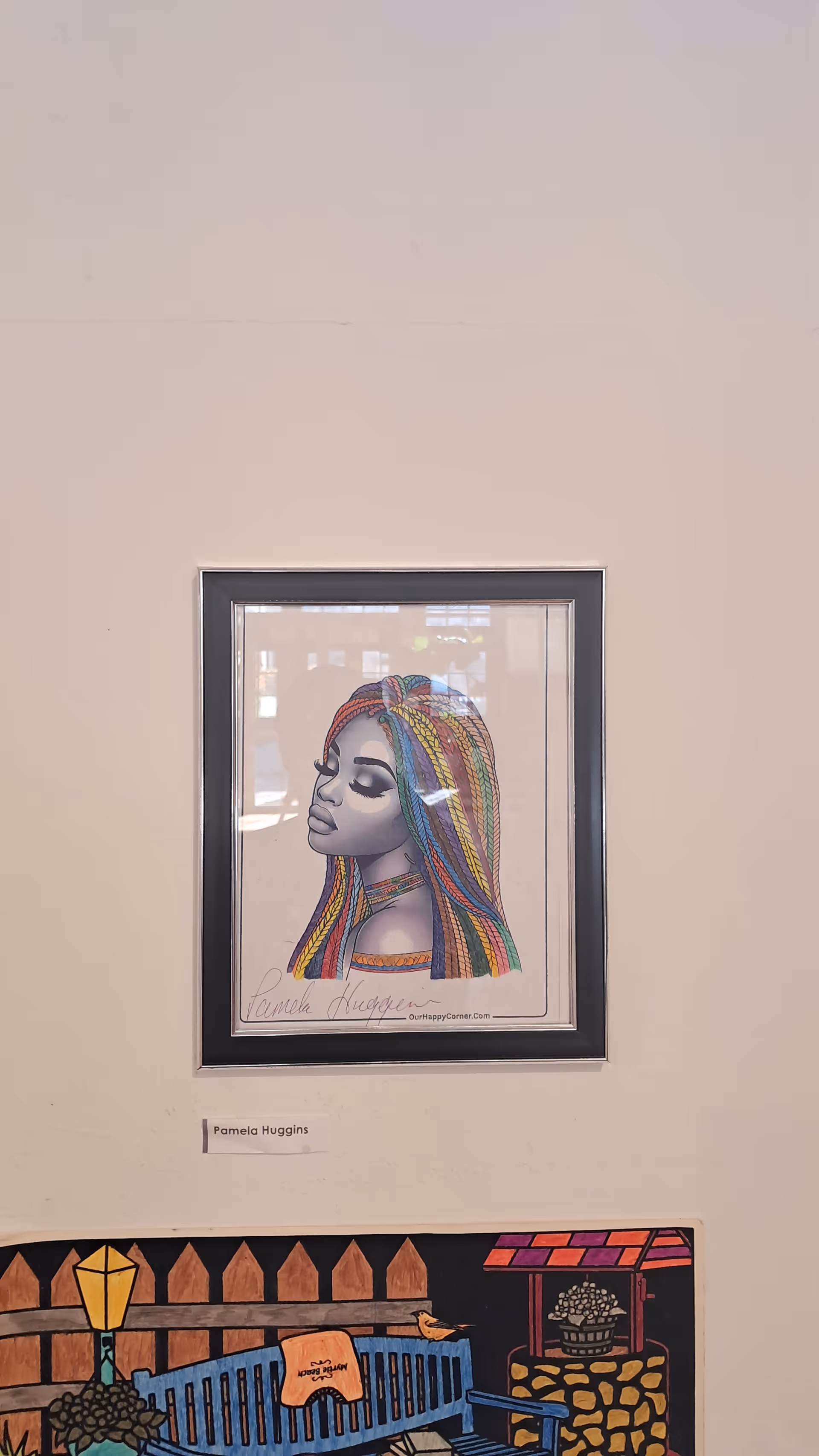 Two framed artworks on a beige wall, with labels beneath, in an interior.
