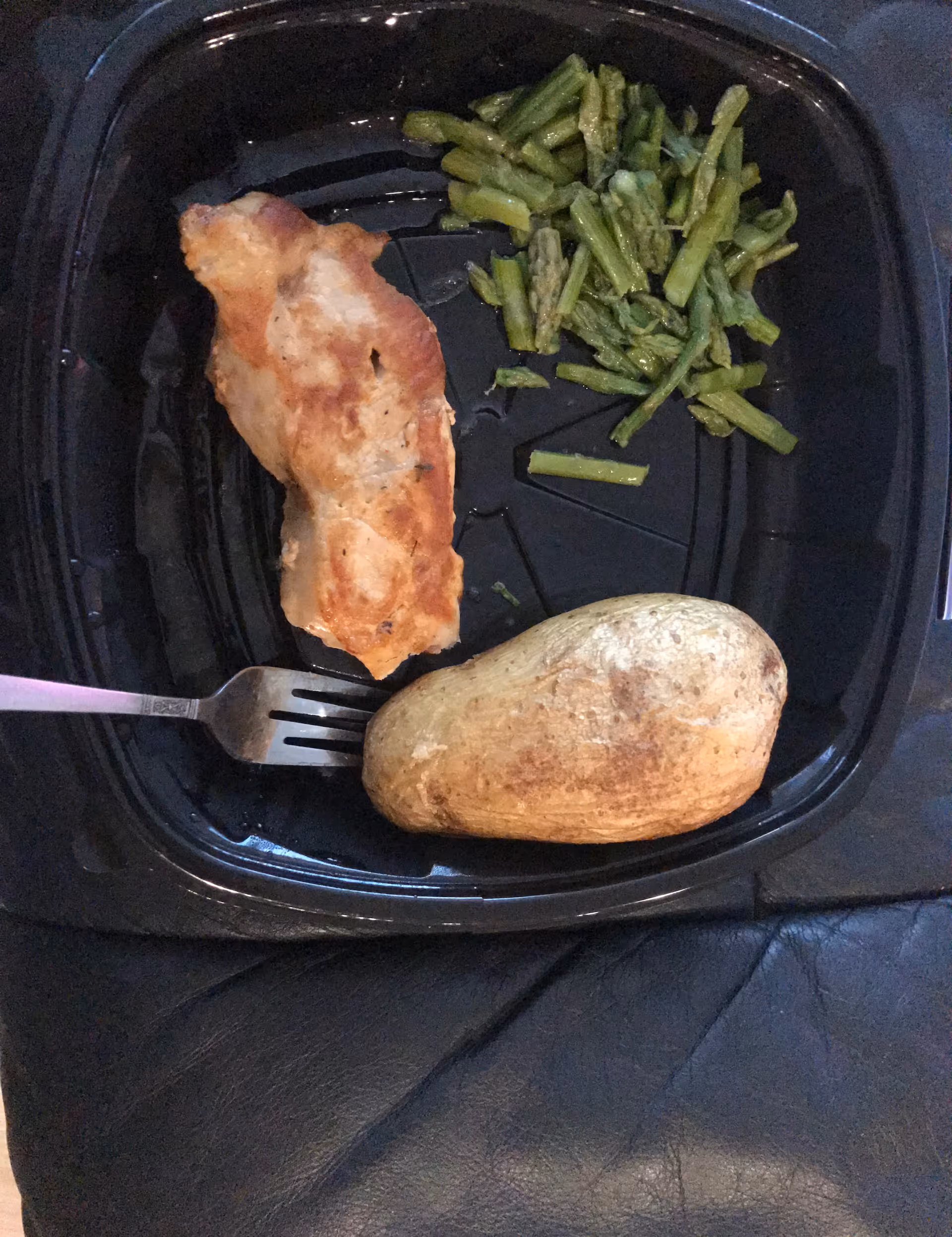 A meal tray with chicken, green beans, and a baked potato.