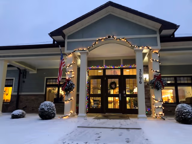 Front entrance of A.R.K Residential Care with holiday lights and wreaths in snow.
