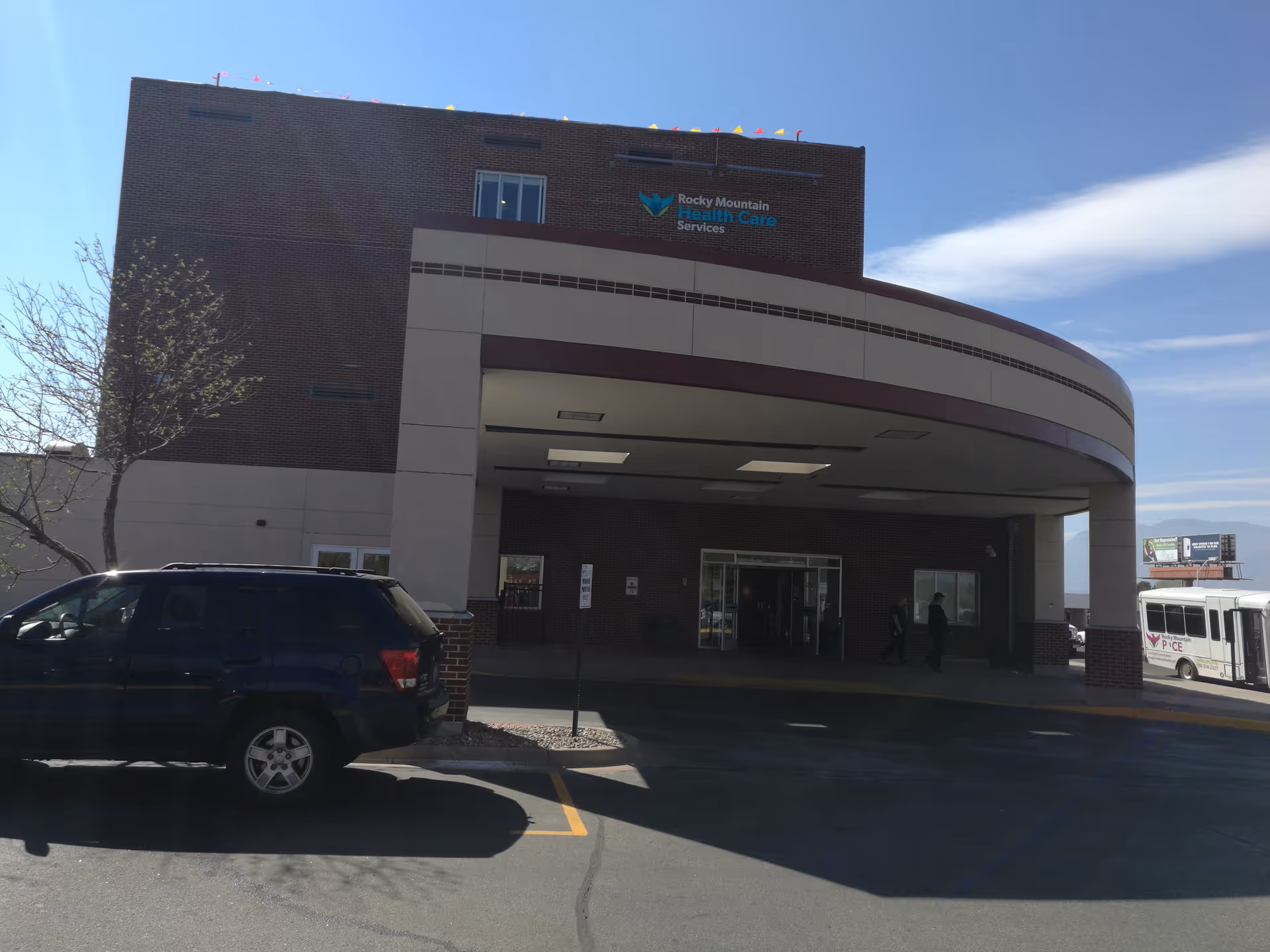 Exterior view of Rocky Mountain Health Care Services building with entrance canopy and parked vehicles