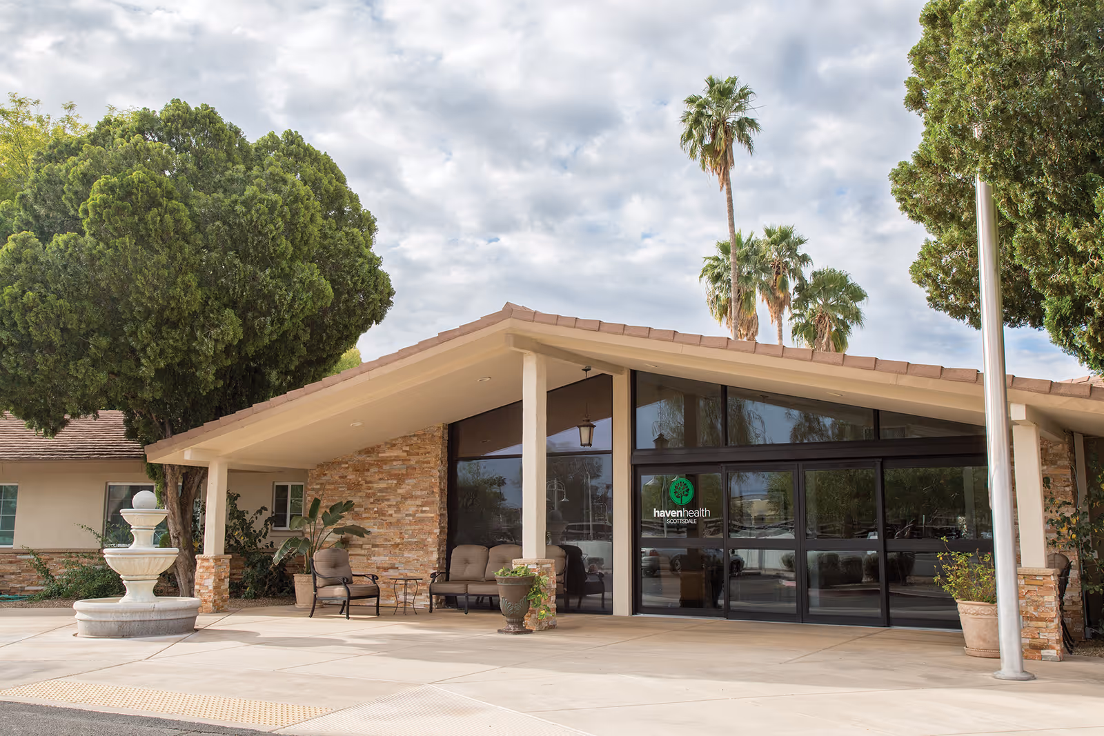 Front entrance of Haven Health Scottsdale with a covered porch, outdoor seating, fountain, and glass doors displaying the facility logo.