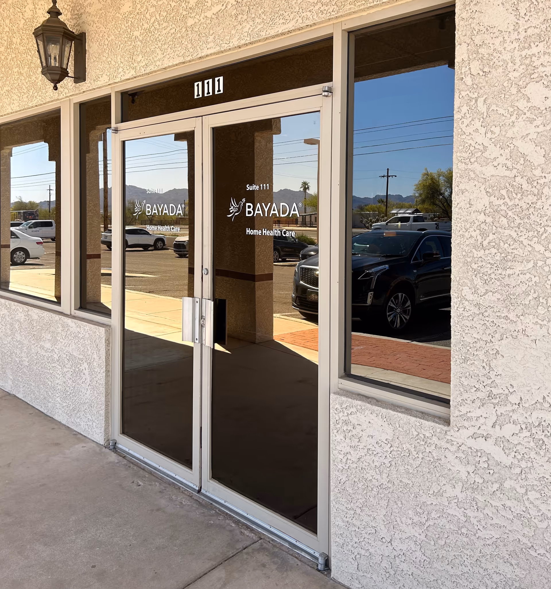 Exterior view of BAYADA entrance with glass doors and parked cars nearby