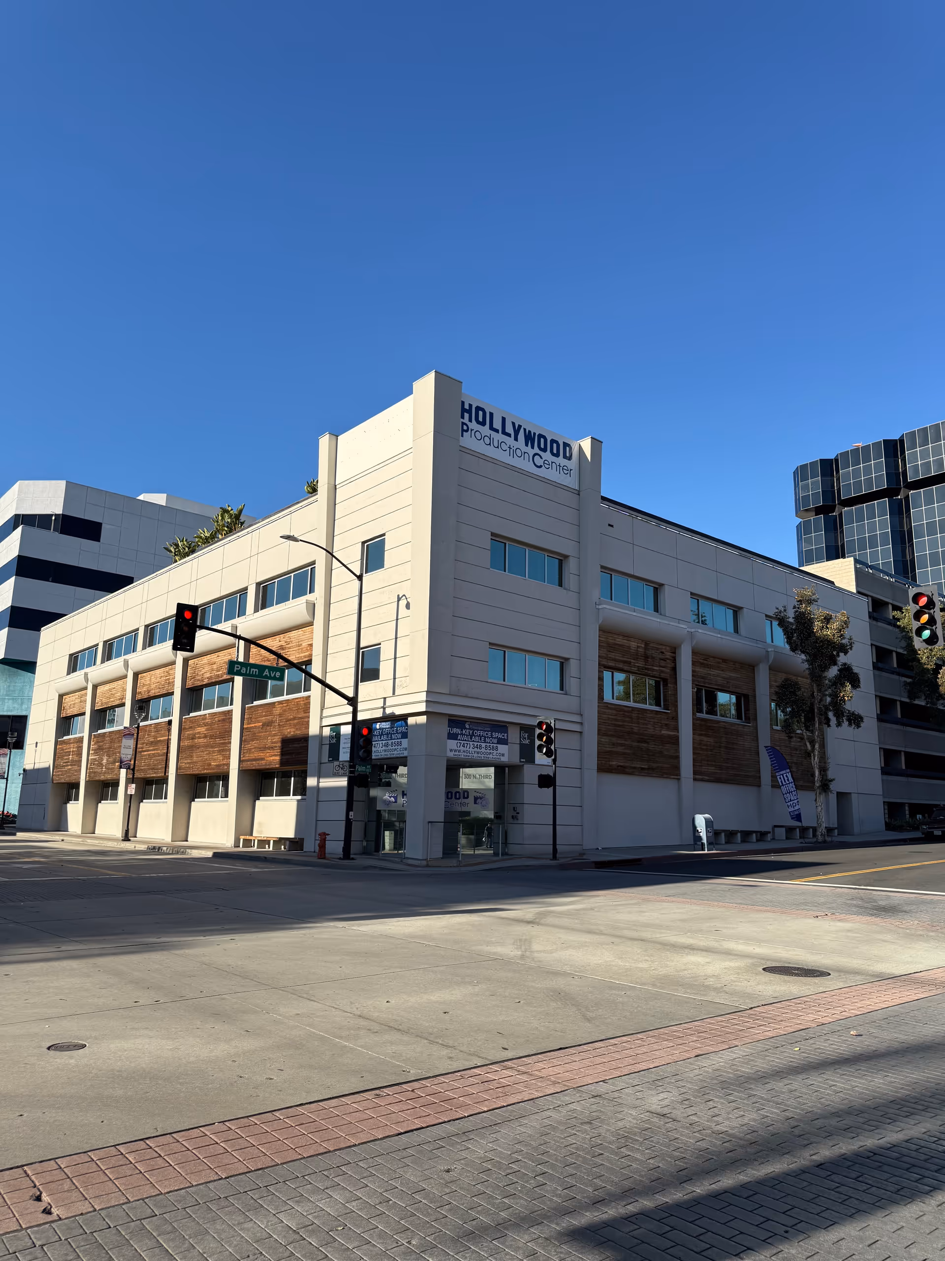 Modern multi-story building on a street corner with Hollywood Production Center signage.