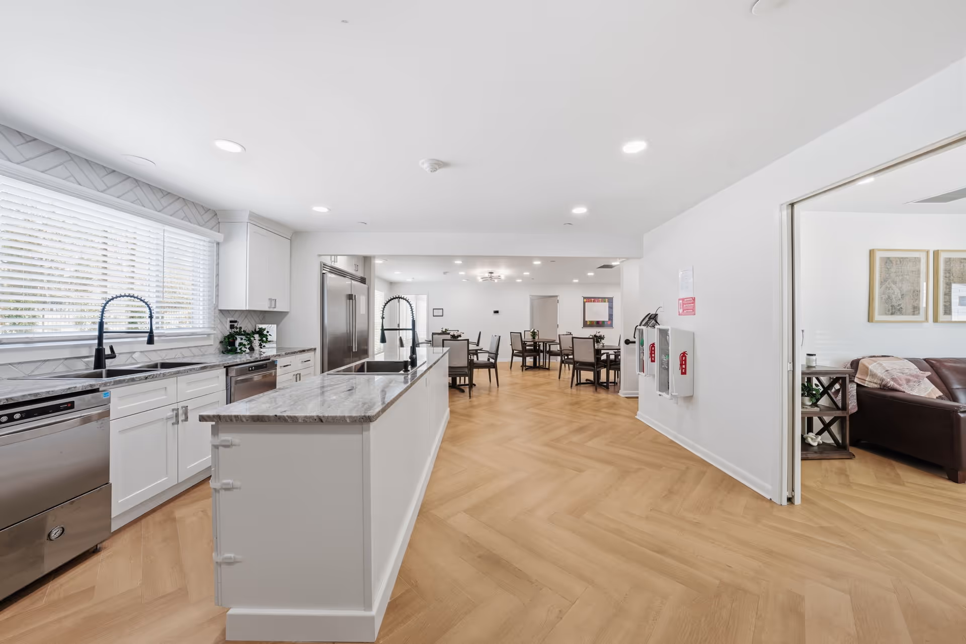 Bright modern kitchen with an island, white cabinets, stainless appliances, and dining area.